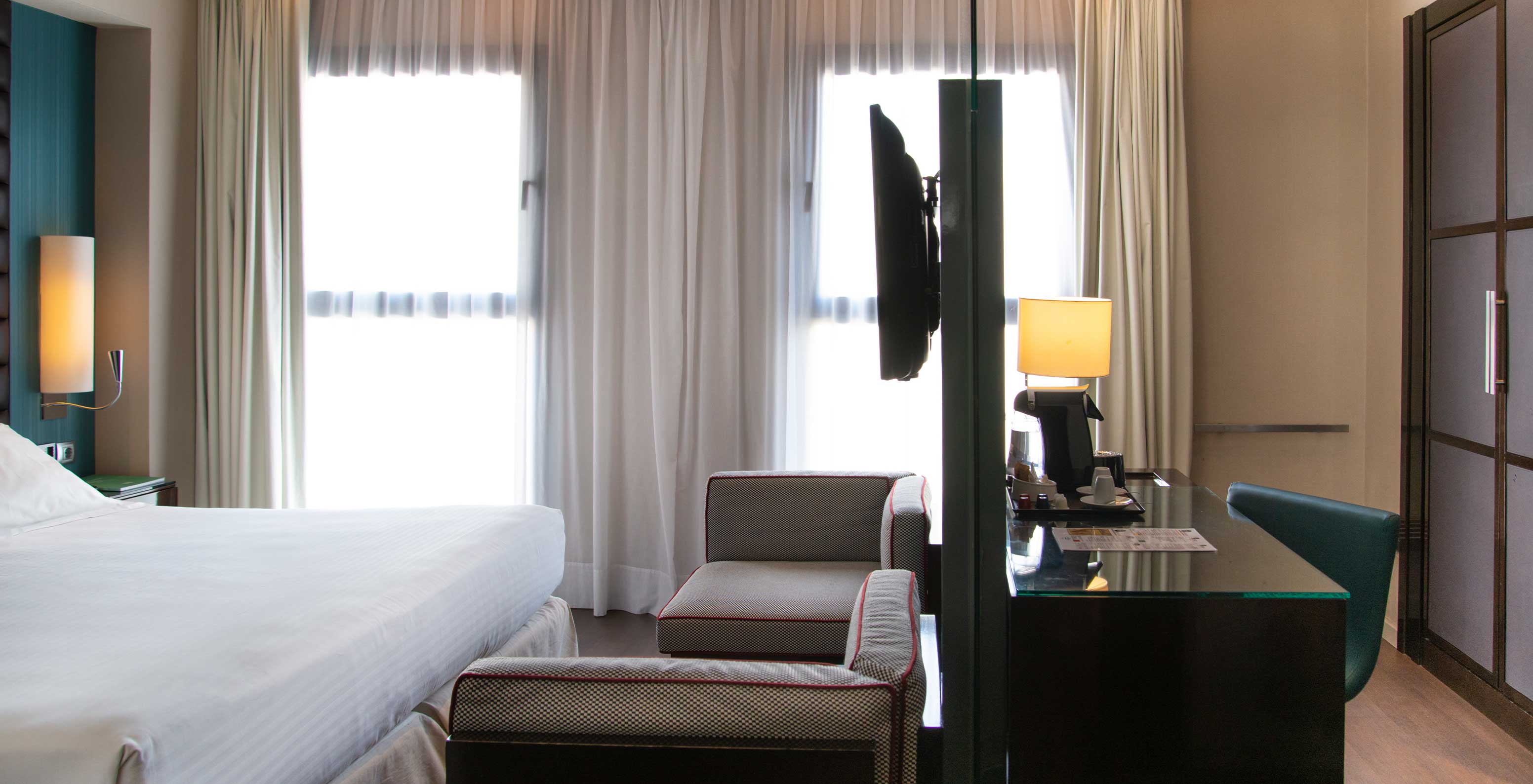 Deluxe King room at Pestana Arena Barcelona has two small sofas, a TV and a desk with amenities