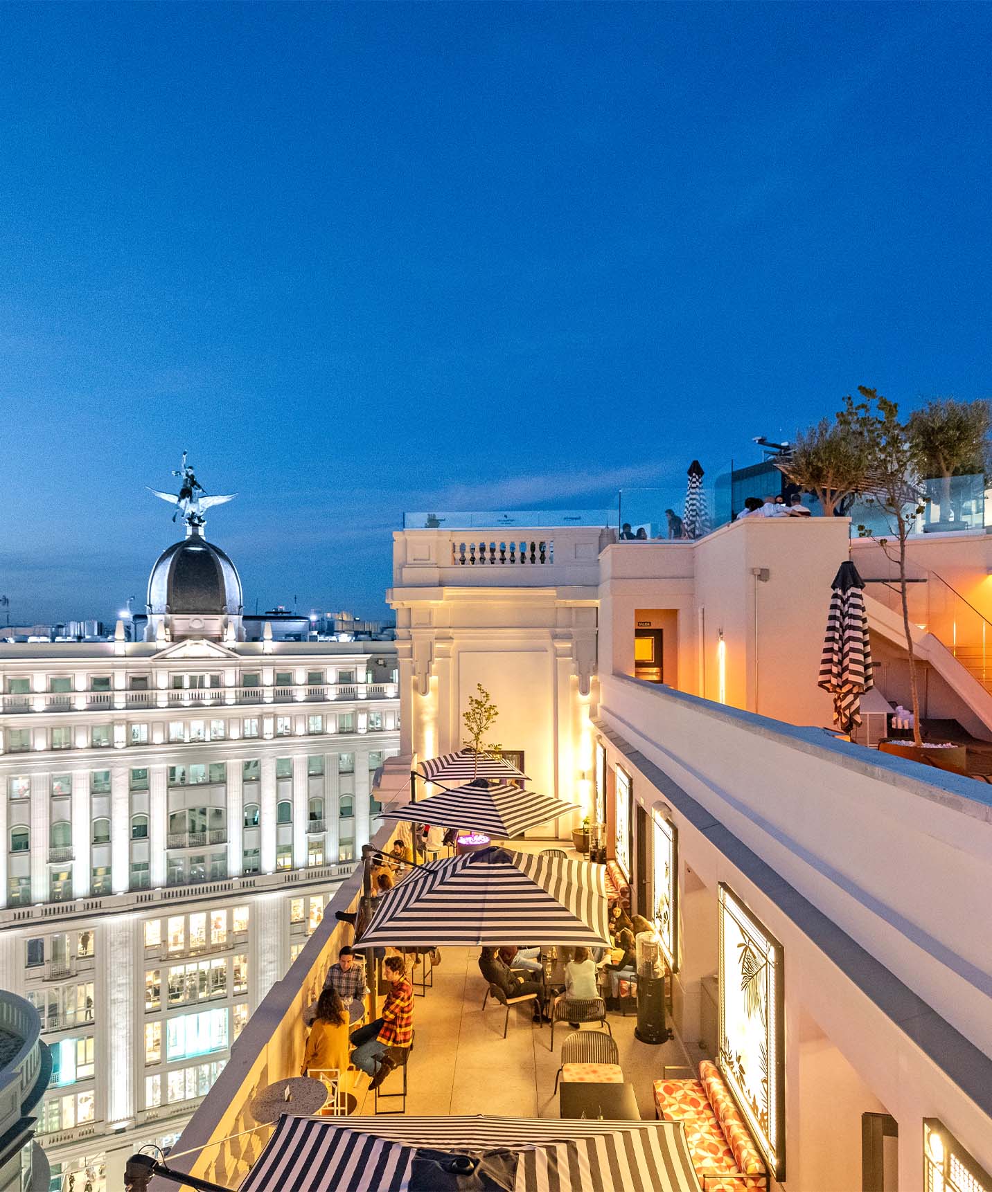 Rooftop of Pestana CR7 Gran Vía with tables and chairs overlooking the restaurant and surrounding white buildings