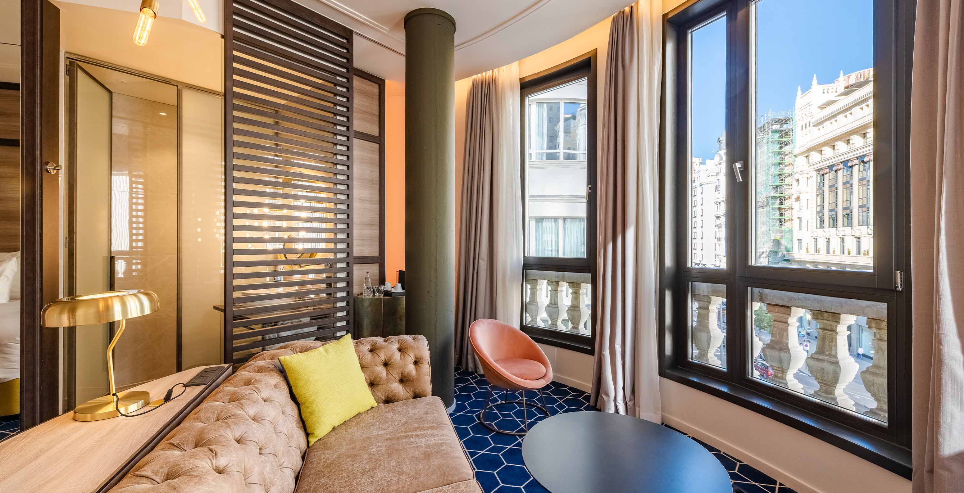 The Amazing CR7 Room at Pestana CR7 Gran Vía Madrid features a sofa, two tables, and large windows overlooking Gran Vía