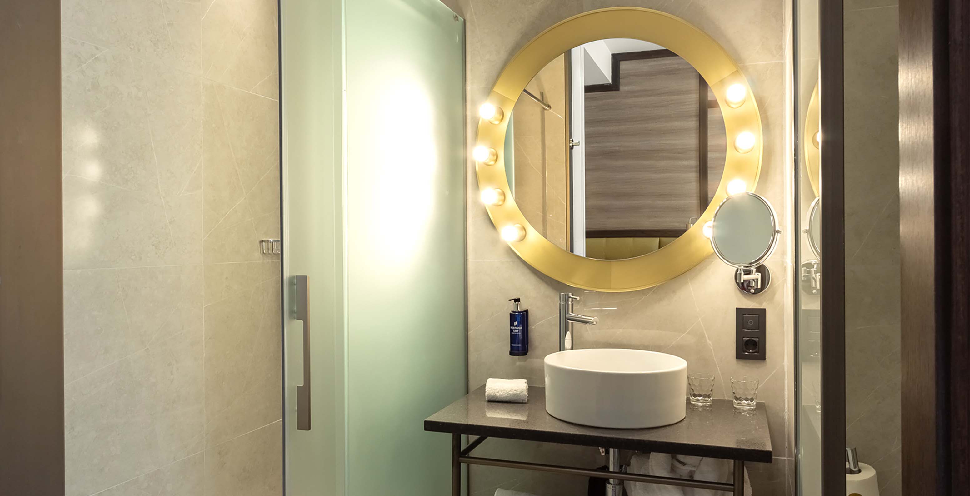 The Deluxe Grand Room at Pestana CR7 Gran Vía Madrid has a bathroom with a mirror, sink, and glass doors