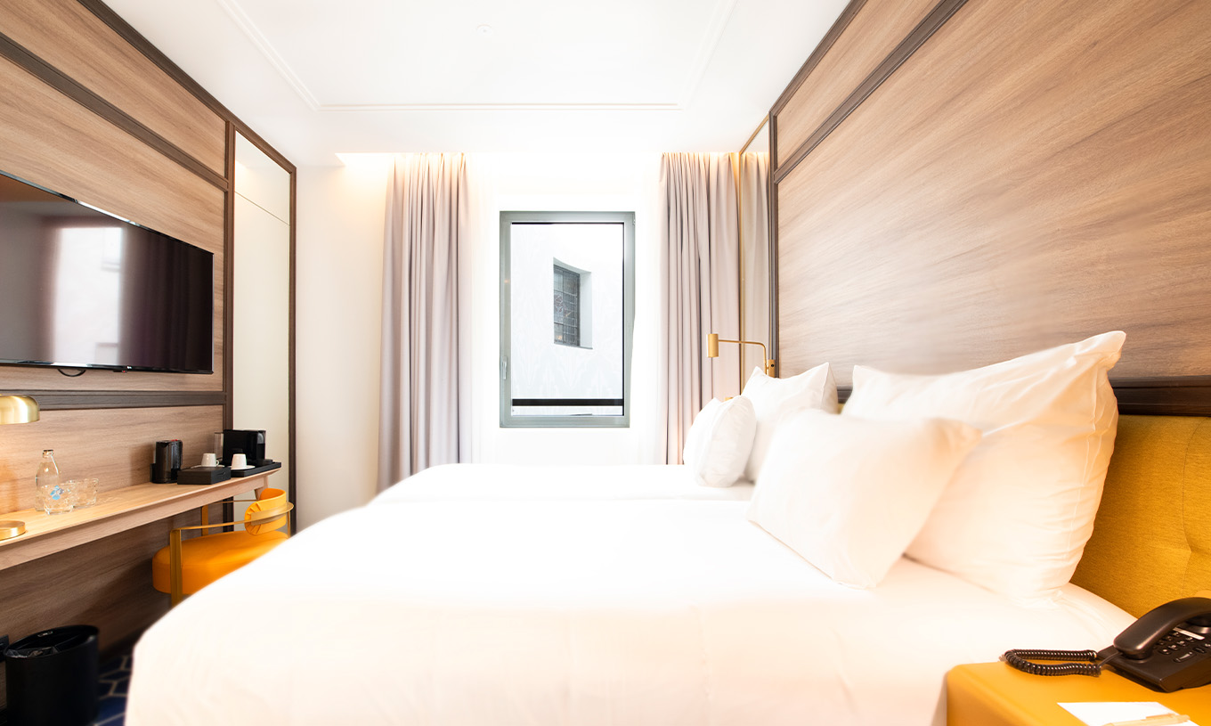 The Small Double Room at Pestana CR7 Gran Vía Madrid has two beds, a TV, a desk, a coffee and tea station, and a chair