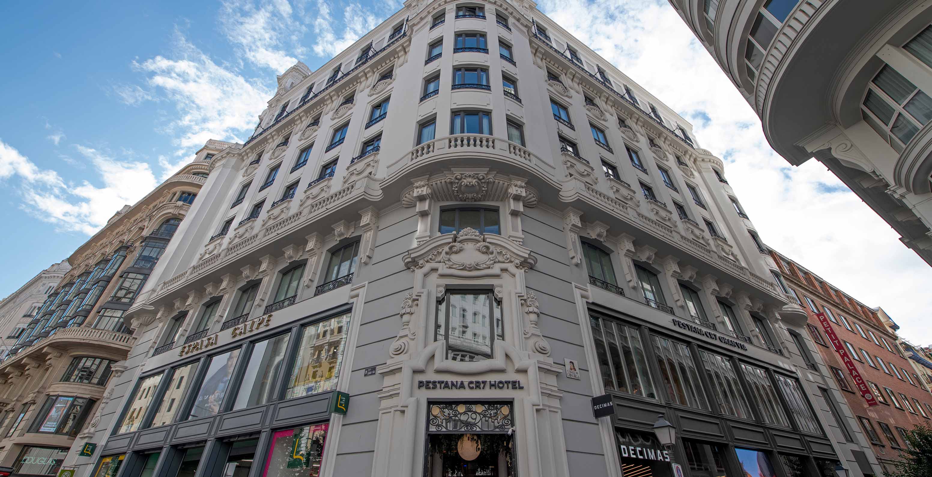 Historic hotel building with entrance door, signage, and street-view shops