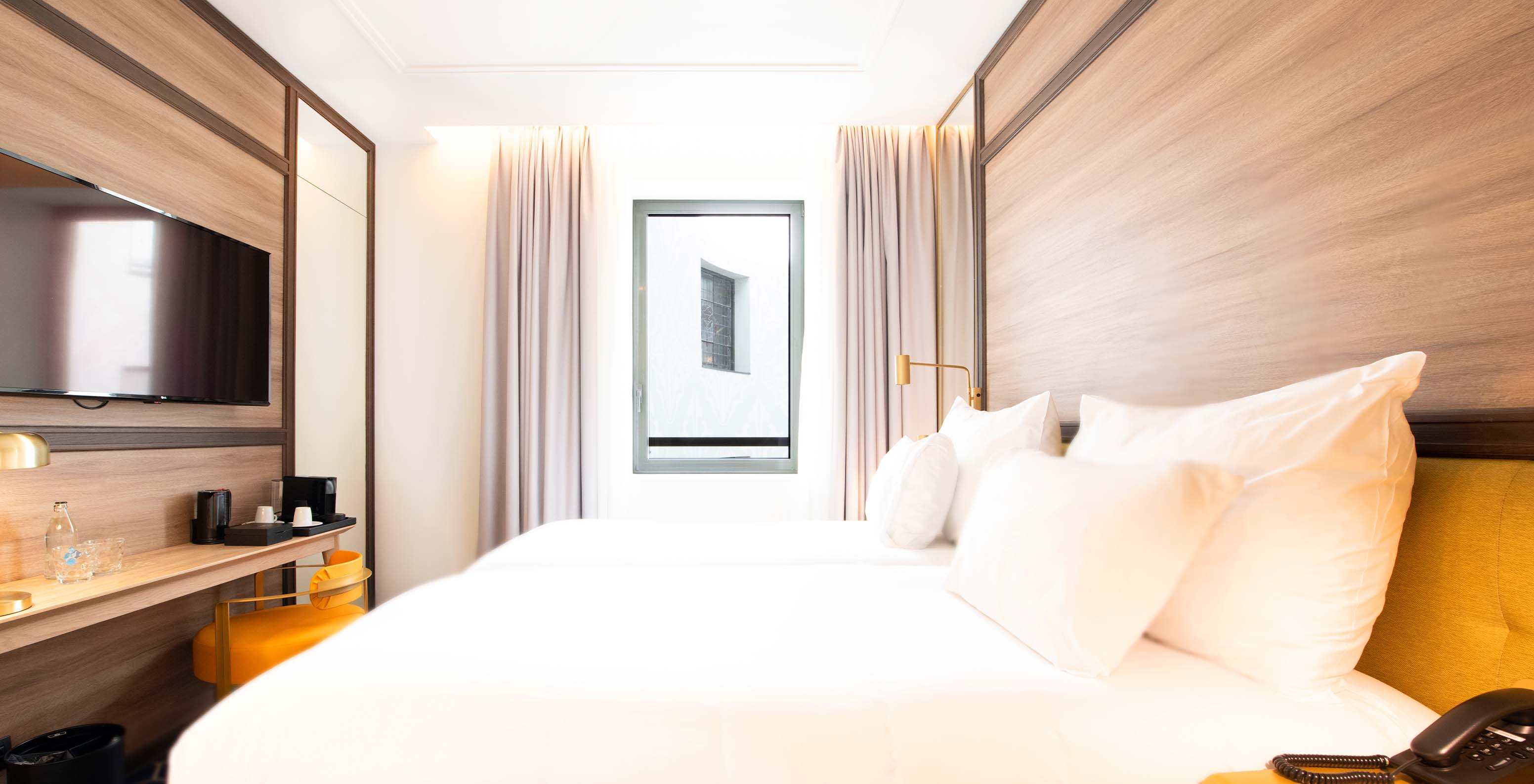 The Cozy Room at Pestana CR7 Gran Vía Madrid includes two beds, a television, desk with coffee and tea station, and a chair