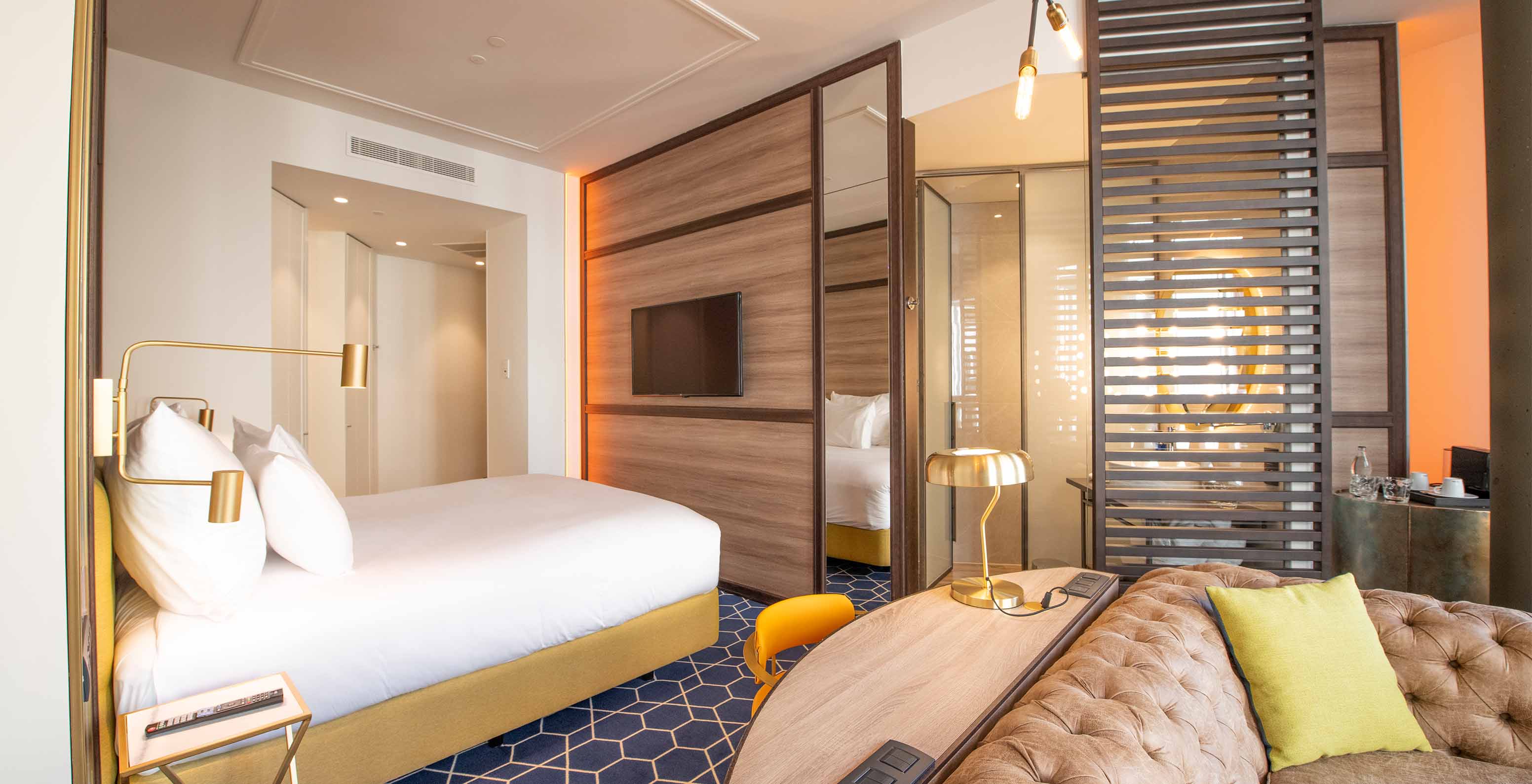 The Fantastic 7 Room at Pestana CR7 Gran Vía Madrid includes a double bed, sofa, desk, mirror, and wooden partition