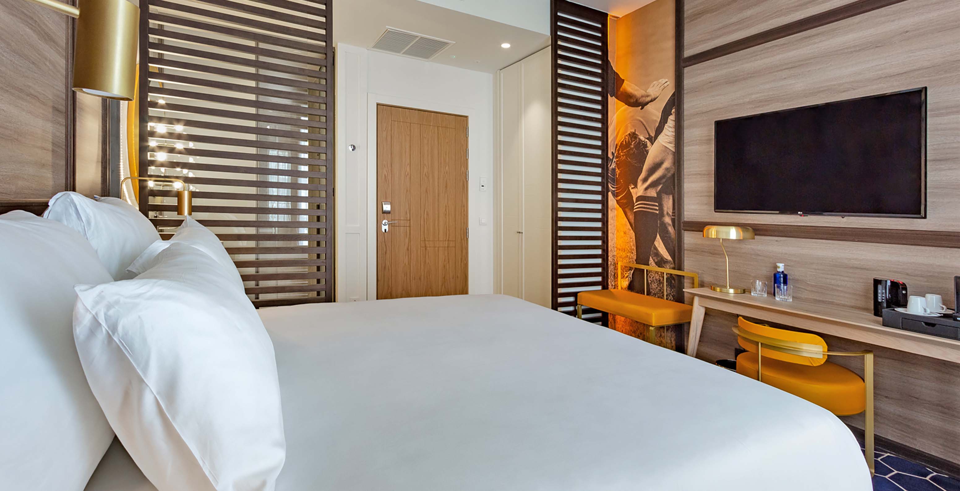 The Premium Room at Pestana CR7 Gran Vía Madrid features a double bed, desk with chair, lamp, bench, and television