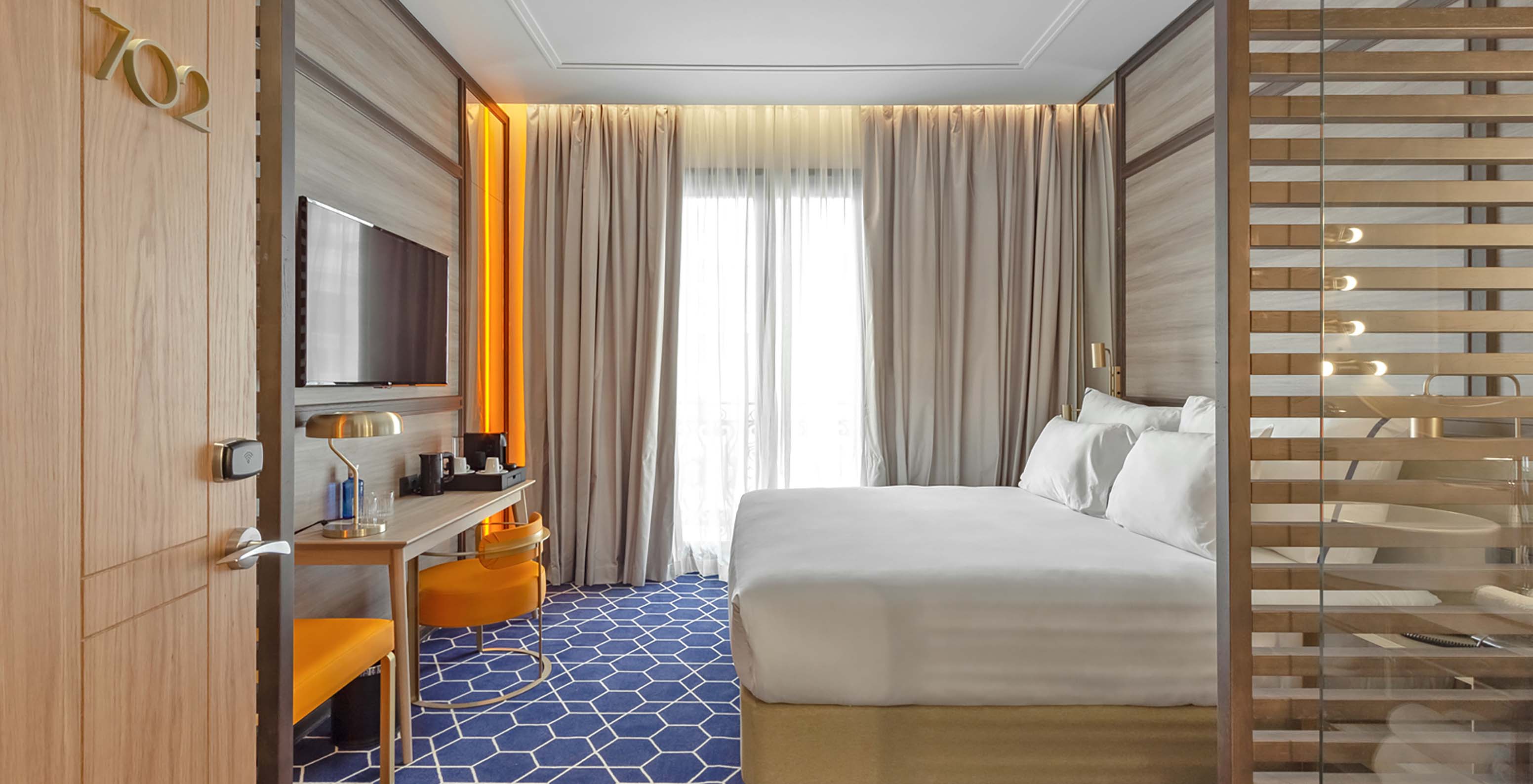 The Premium Room at Pestana CR7 Gran Vía Madrid includes a double bed, desk, chair, television, and curtained window