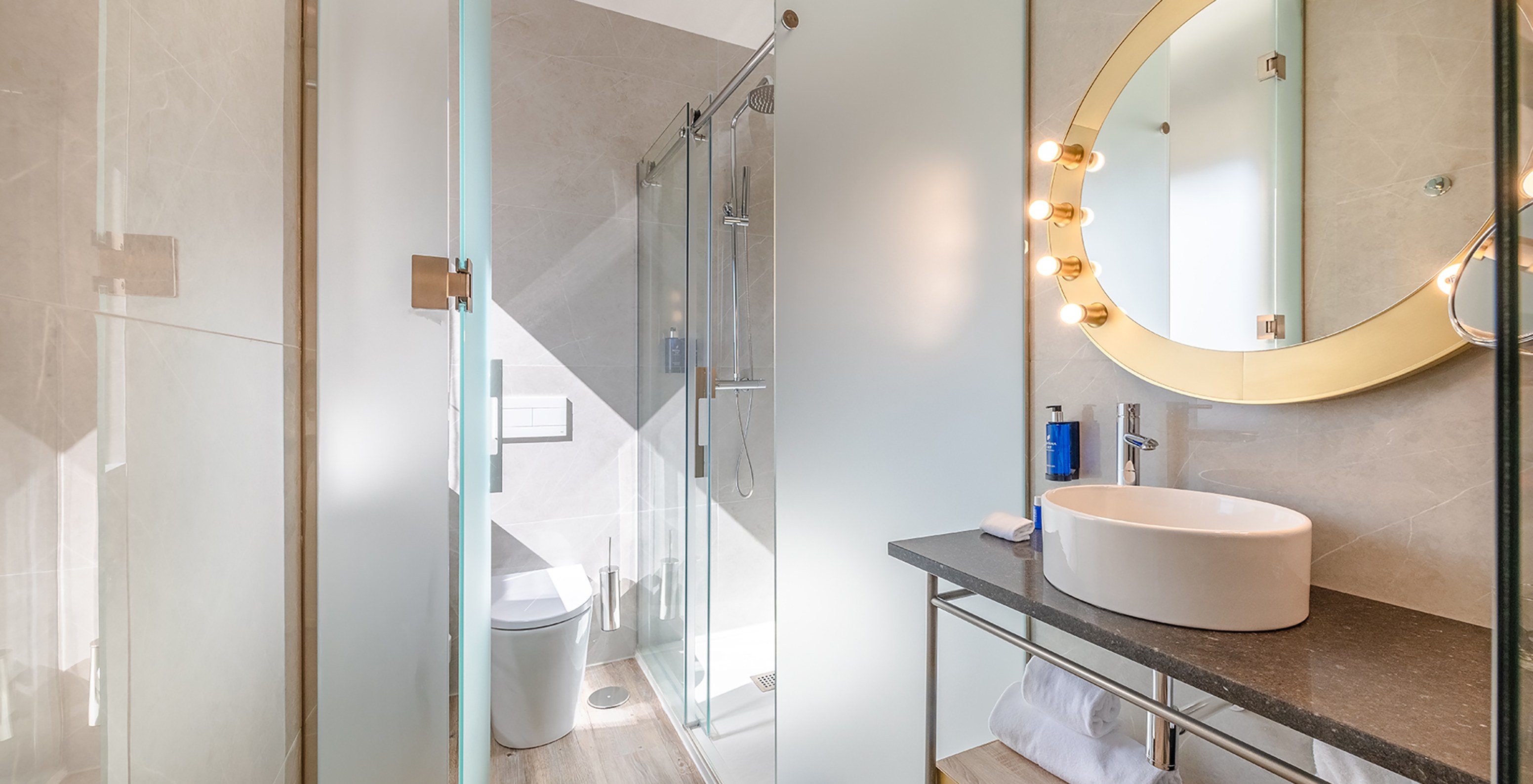 The Small Double Room at Pestana CR7 Gran Vía Madrid has a bathroom with a round mirror, toilet, and shower