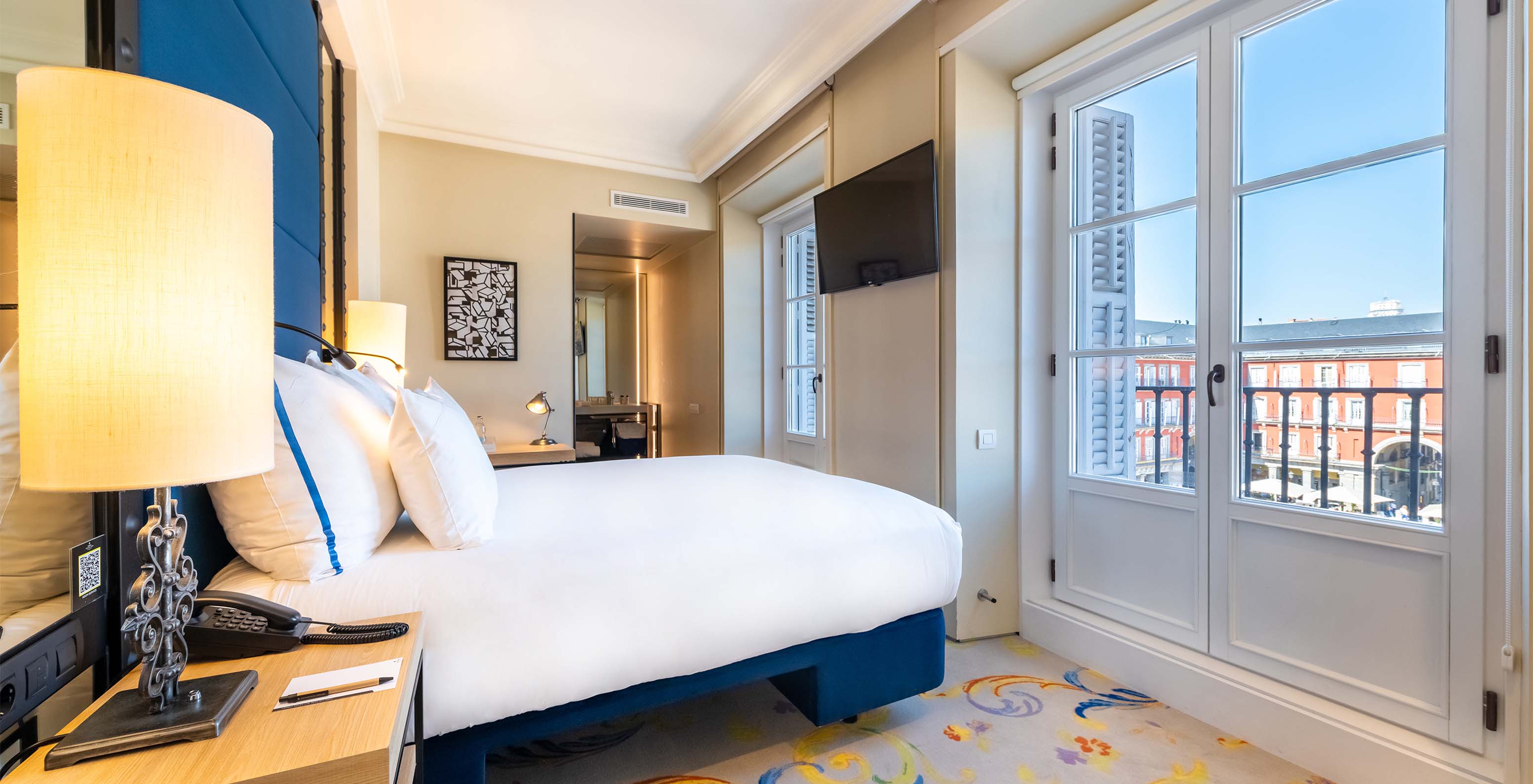 The Deluxe Grand Plaza Mayor at Pestana Plaza Mayor Madrid has a double bed and a window with a view of Plaza Mayor