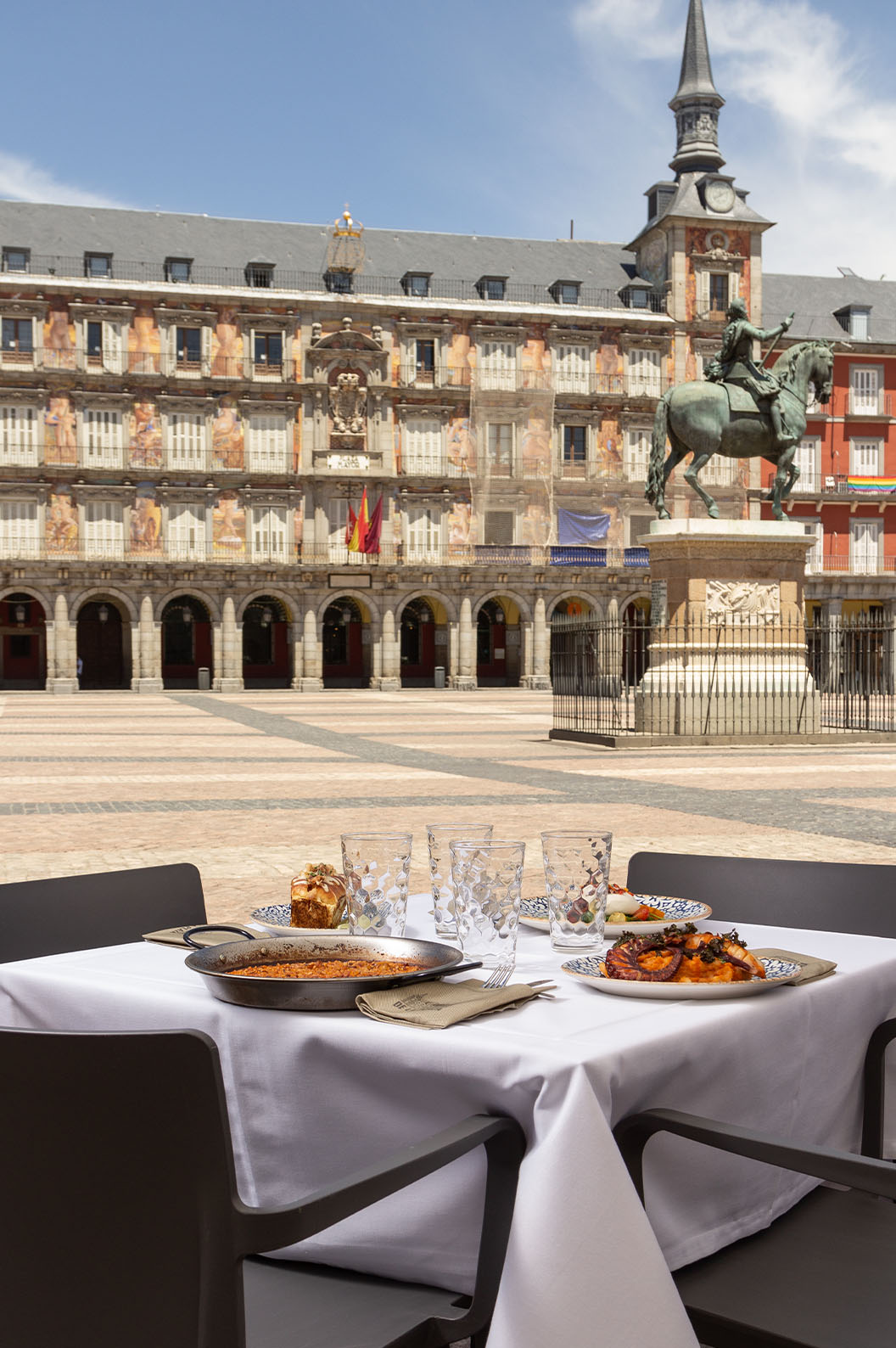 View of the restaurant terrace at Pestana Plaza Mayor Madrid on a sunny day with a view of the Felipe III statue