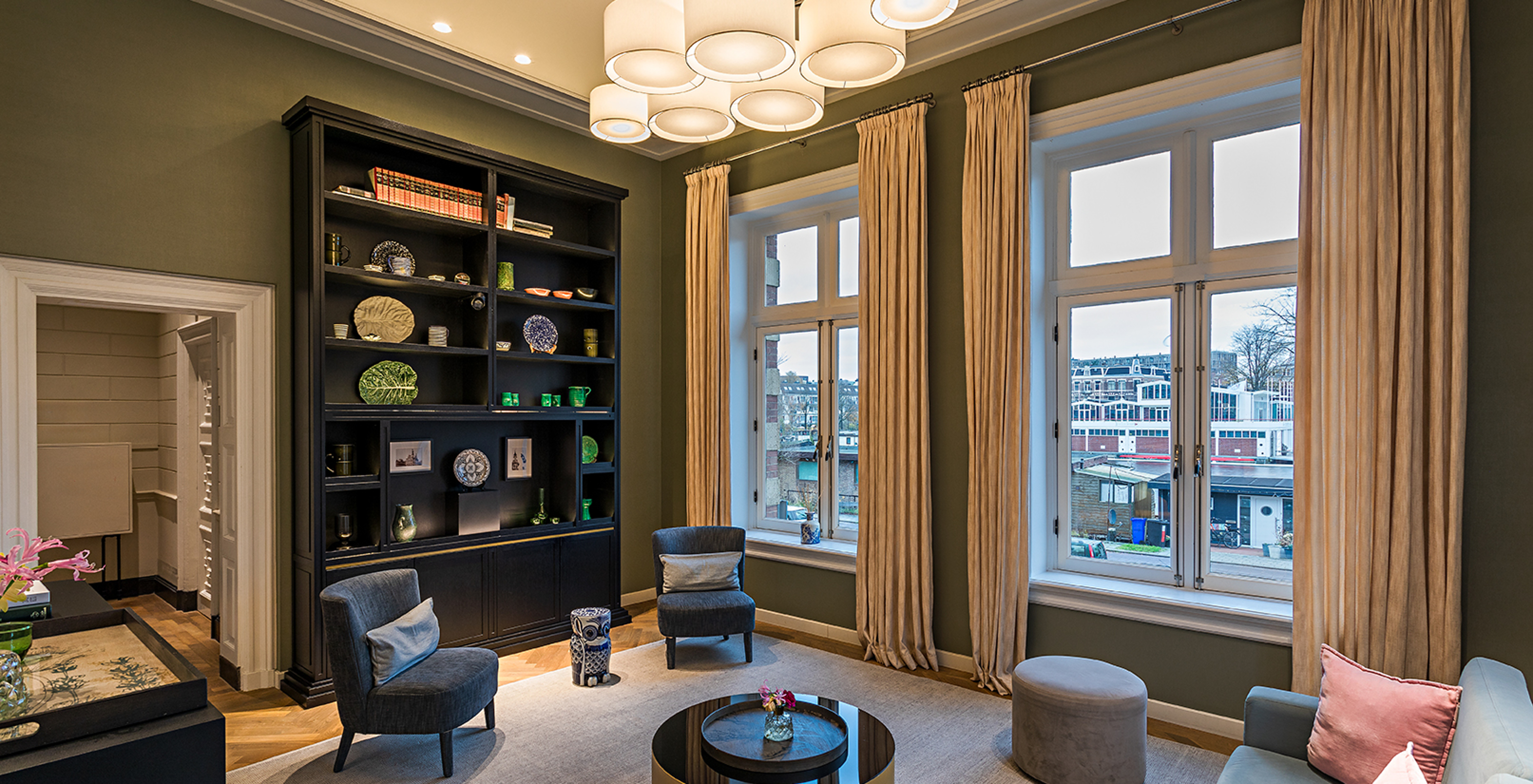 The Pestana Amsterdam Riverside has a living room with tables and chairs and a black cupboard