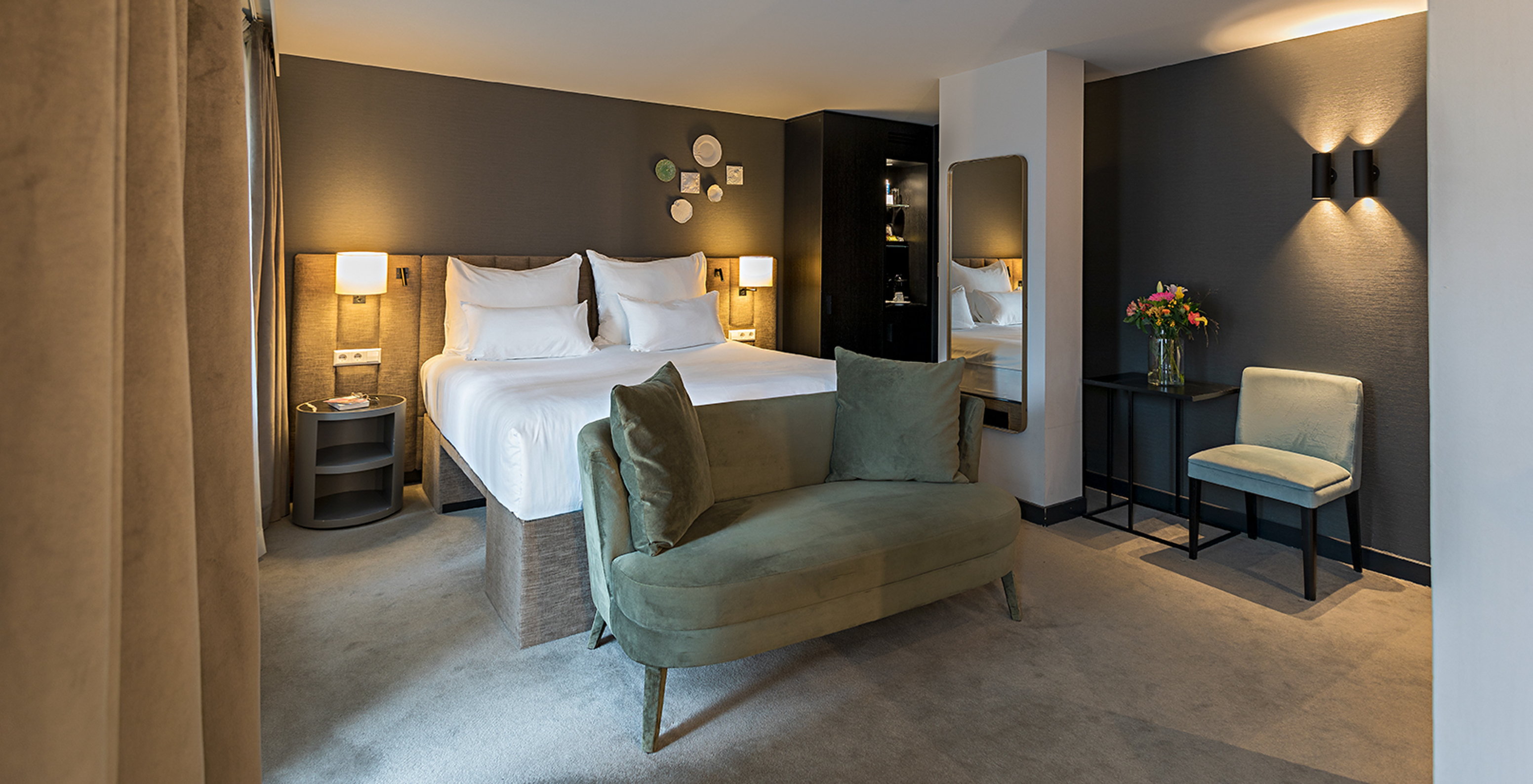 Deluxe room at Pestana Amsterdam Riverside has a double bed, bedside table, and a sofa in front of the bed