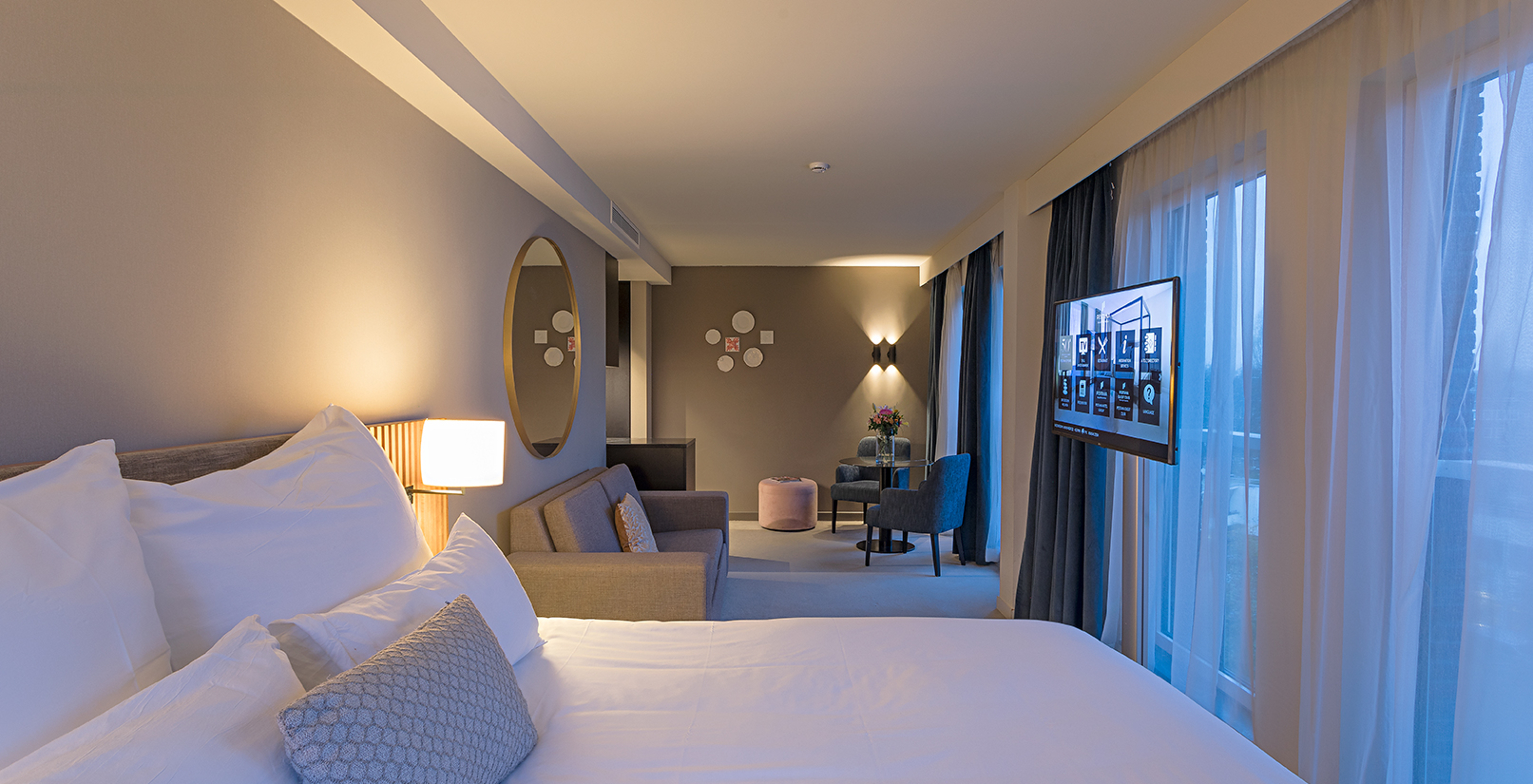 Premium Studio room at Pestana Amsterdam Riverside has a double bed, gray sofa, a mirror and two chairs