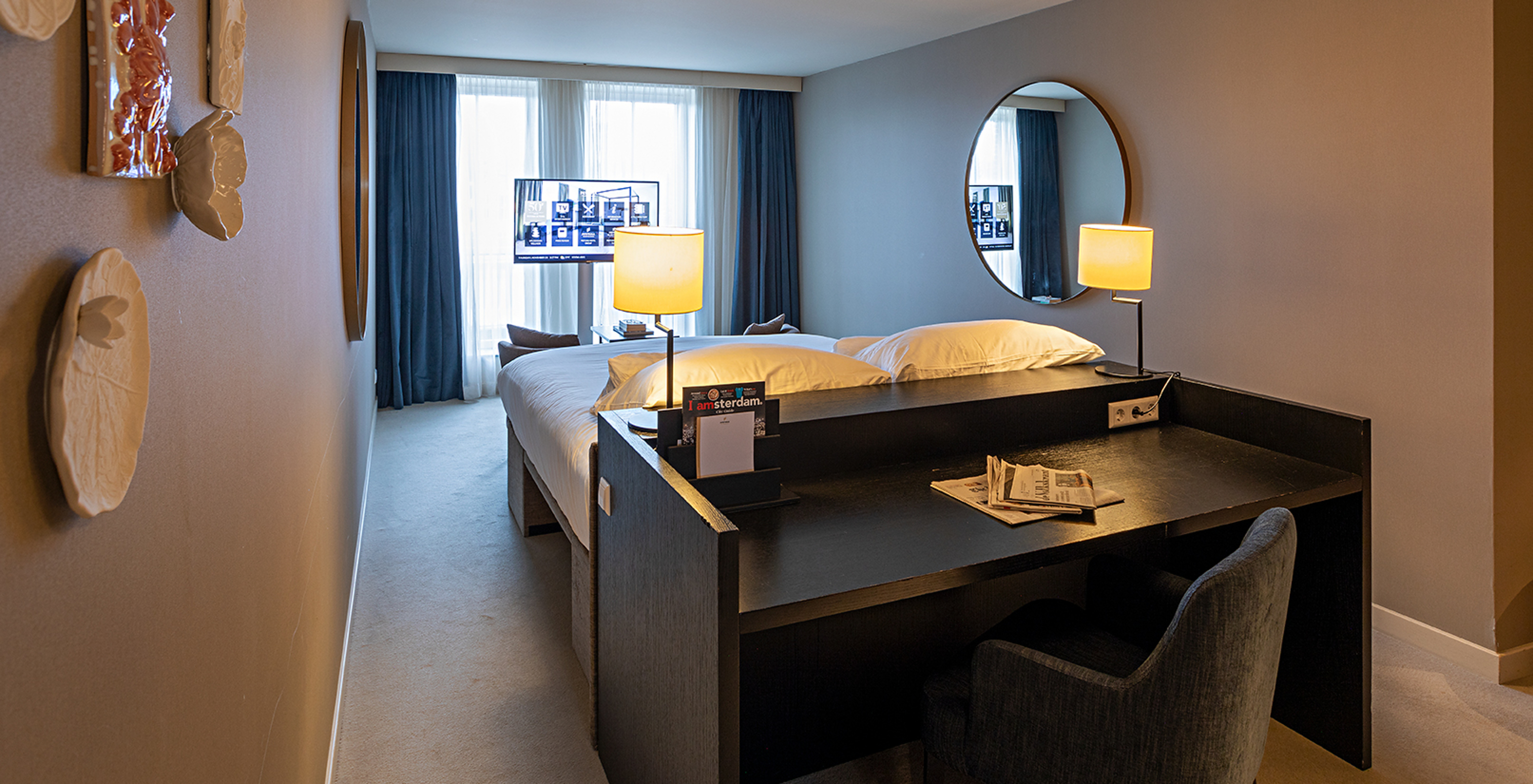 Executive - River View room at Pestana Amsterdam Riverside has a TV in front of the bed and a desk