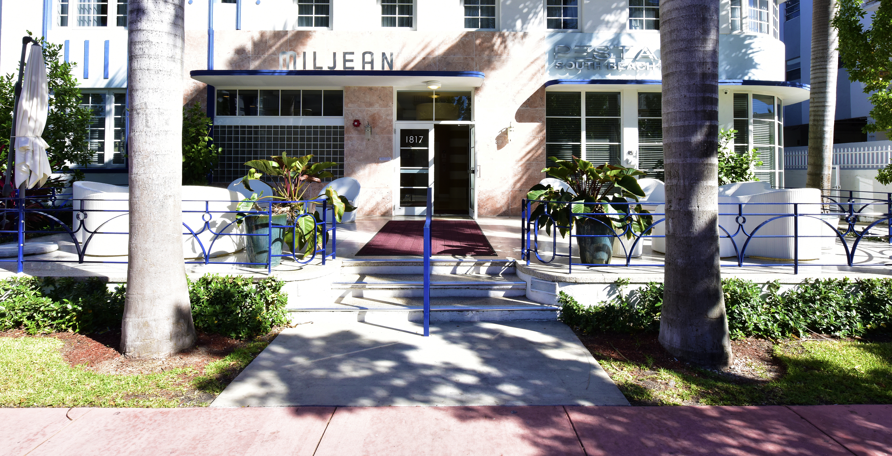 View of the entrance of Pestana Miami South Beach with chairs, tables, and the hotel facade in the background