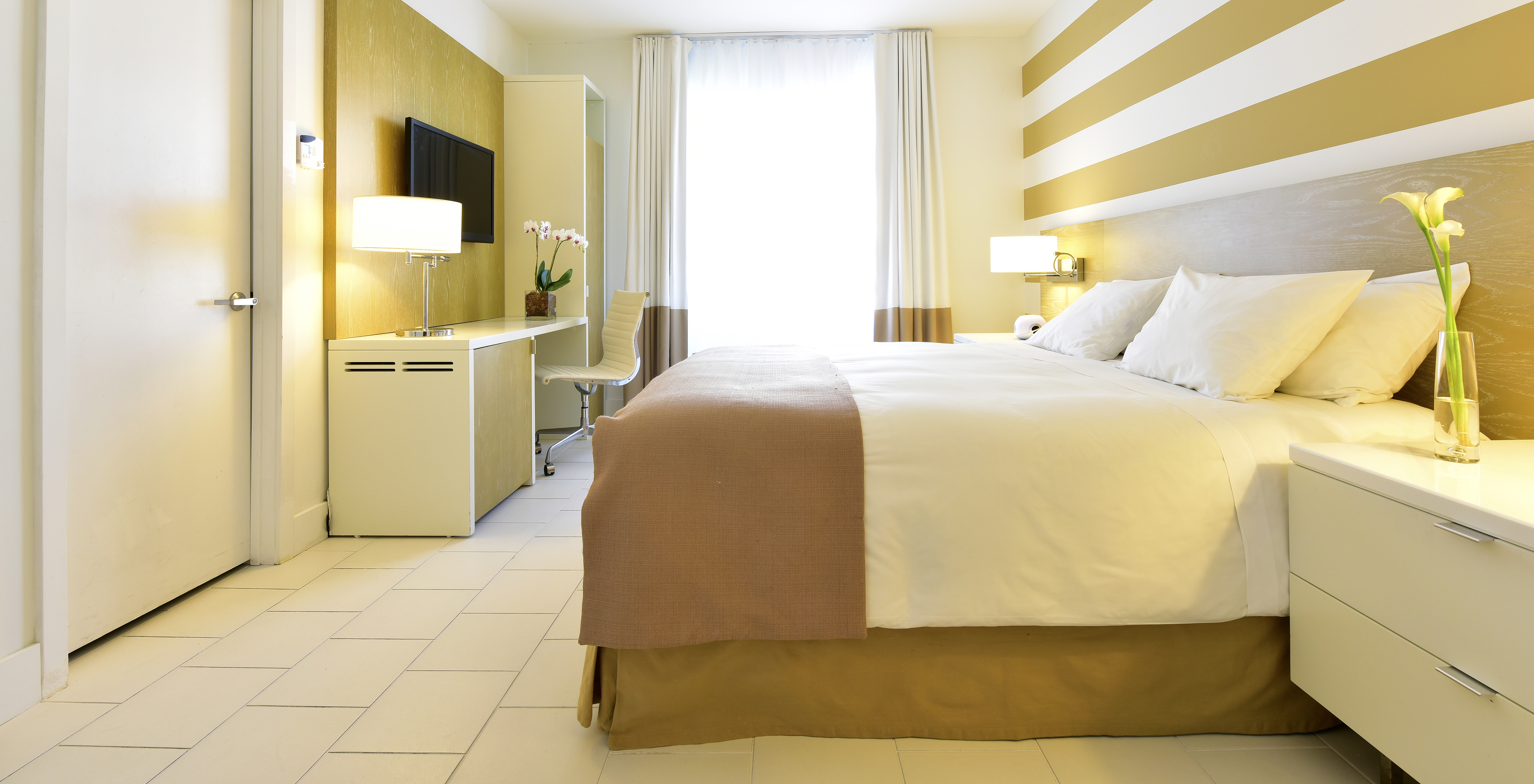 The Art Deco King - ADA Room at Pestana Miami South Beach has a double bed, bedside table, table and TV