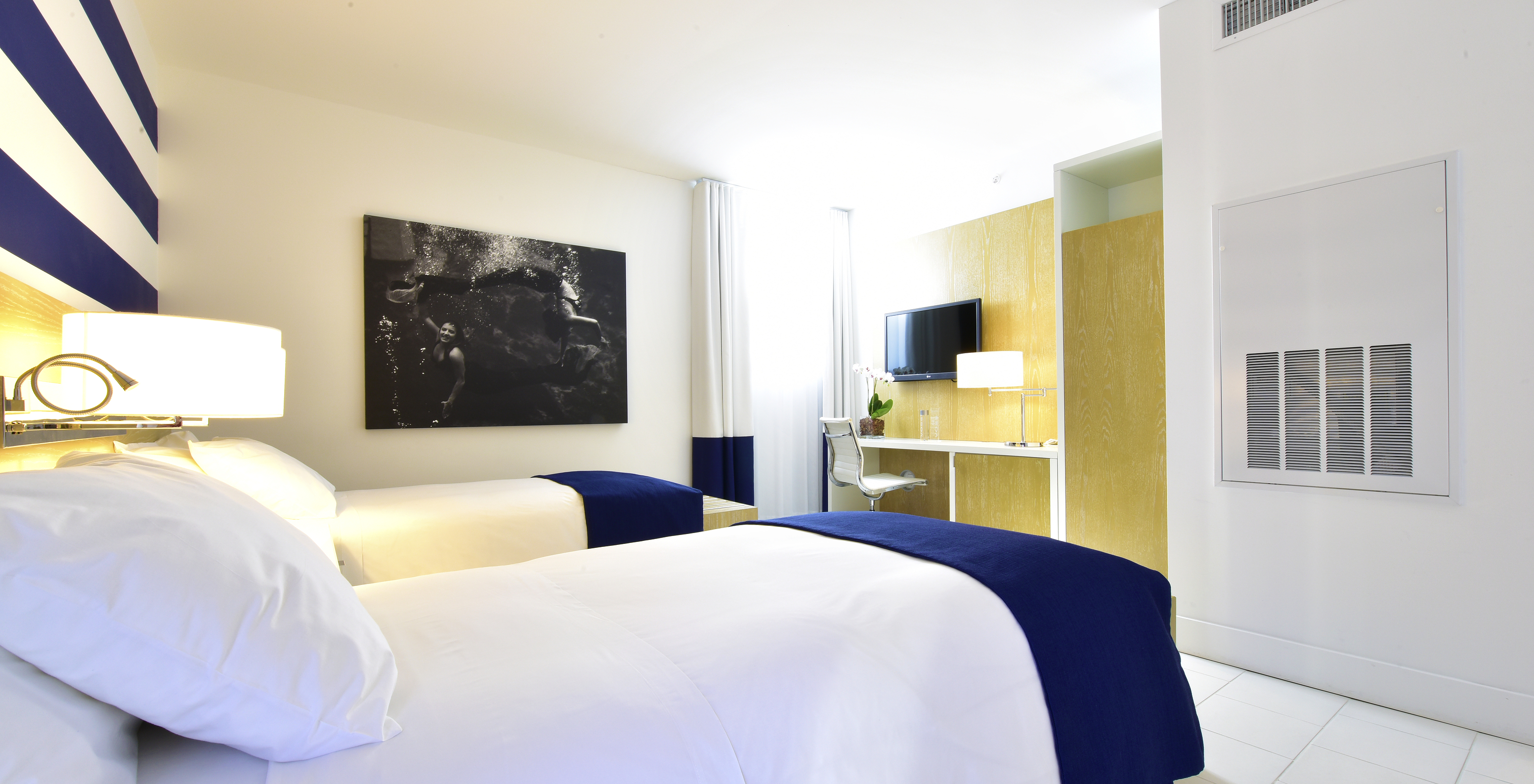 The Art Deco Double Room at Pestana Miami South Beach has two single beds, TV, table and a large painting