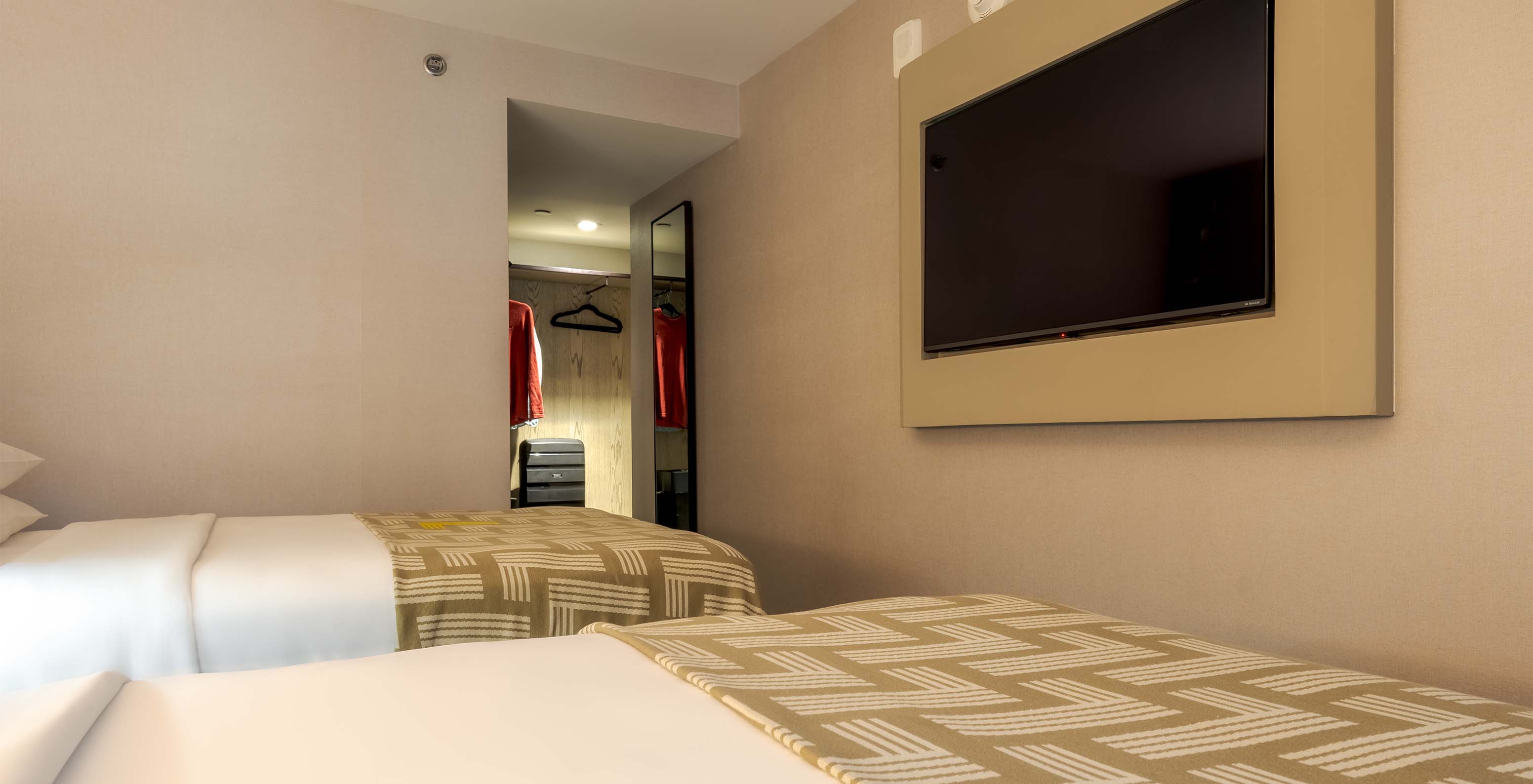 The Comfort Double ADA at Pestana CR7 Times Square has two beds with a bedspread with the number seven and a TV