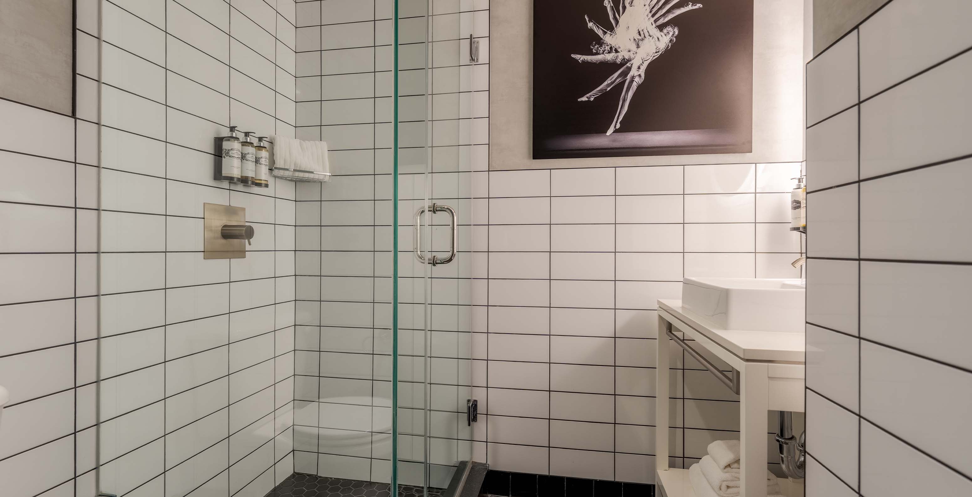 The Comfort Street View at Pestana CR7 Times Square has a bathroom with a shower, geometric patterned floor, and a painting