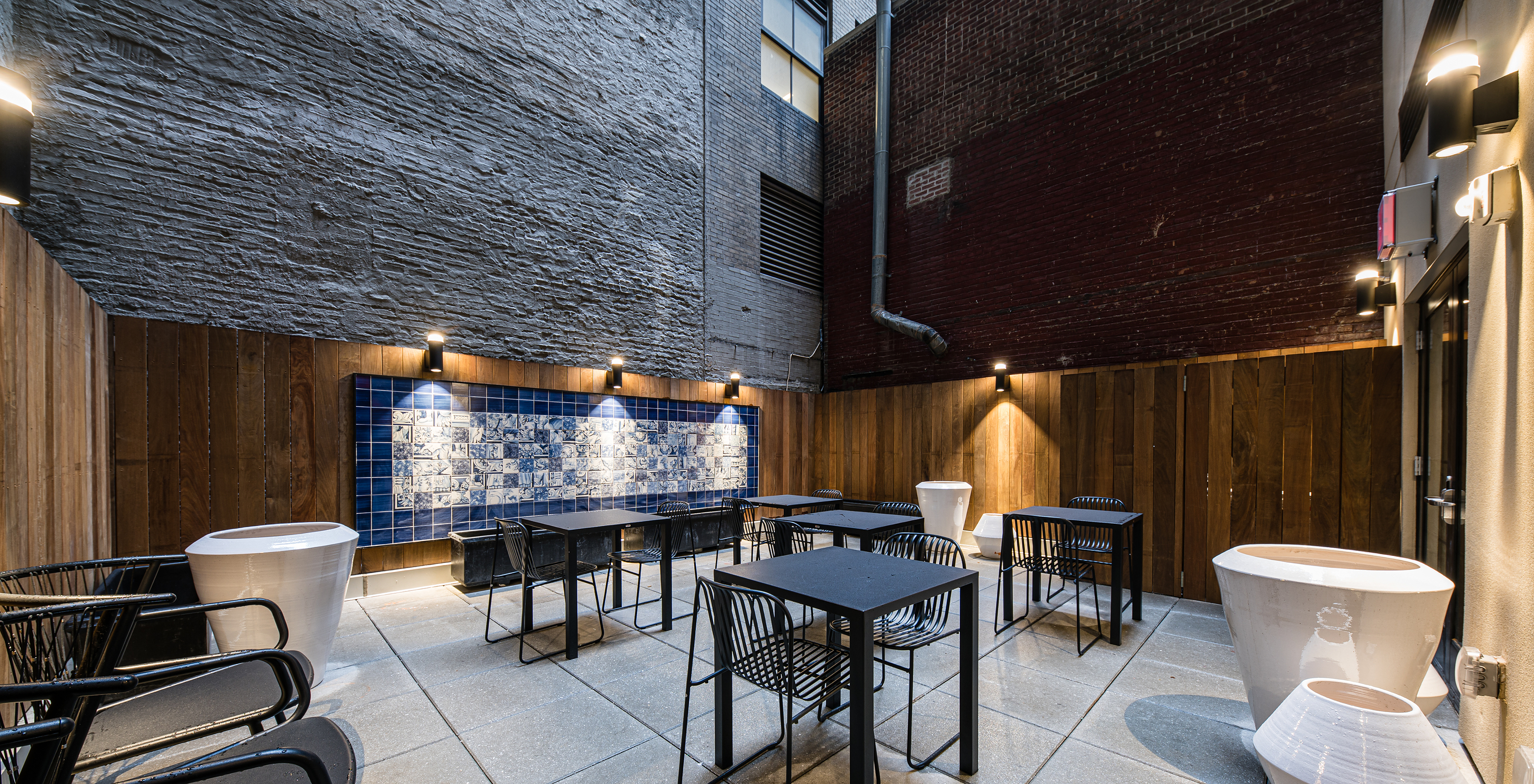 Outdoor patio of Pestana Park Avenue with tables and chairs, decorated with a tiled mural and potted plants