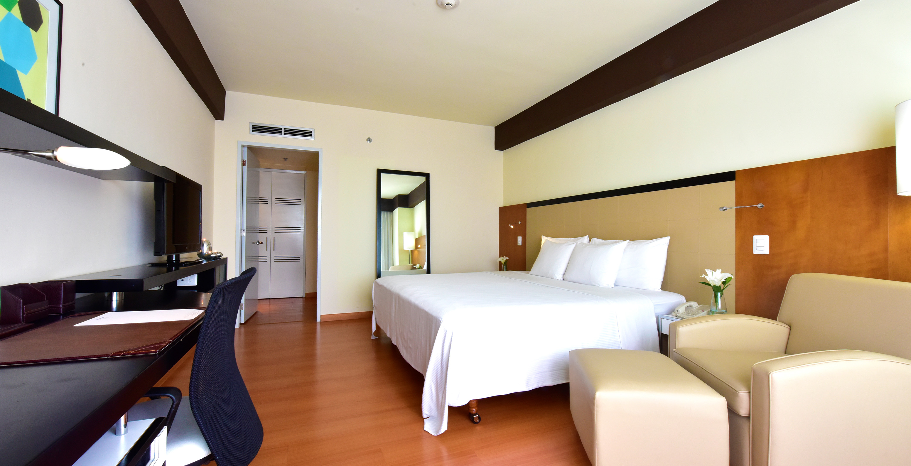 The Executive King Room at Pestana Caracas has a double bed, a large mirror, a desk, and an armchair