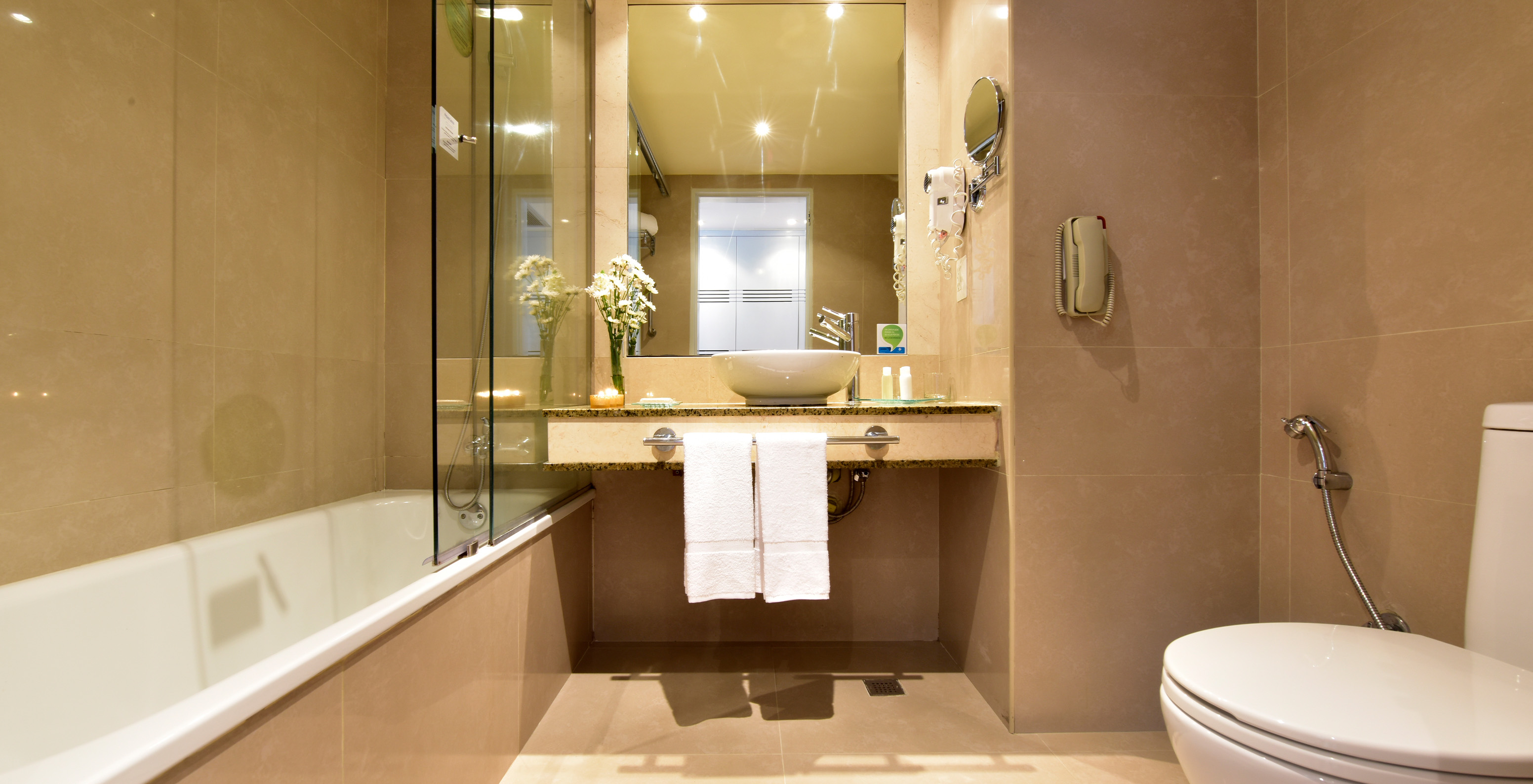 The Twin Junior Suite at Pestana Caracas has a bathroom with a bathtub, sink, mirror, hairdryer, and toilet