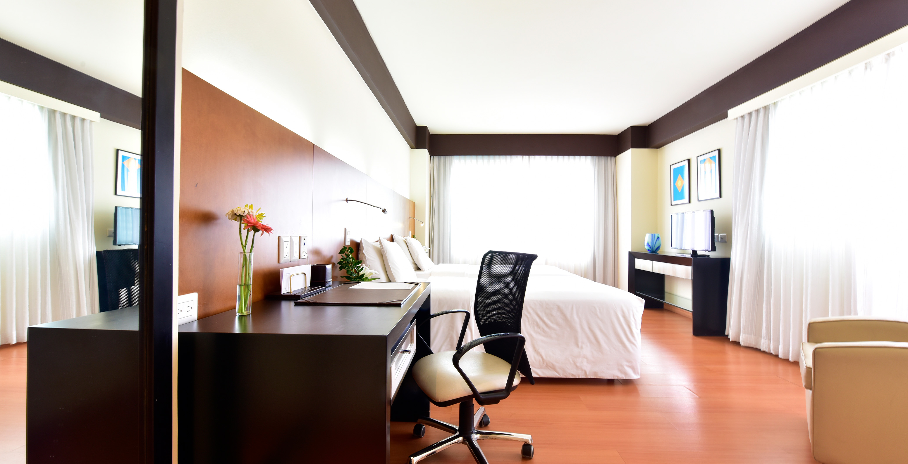 The Twin Junior Suite at Pestana Caracas has a double bed, a desk with an ergonomic chair, and a TV