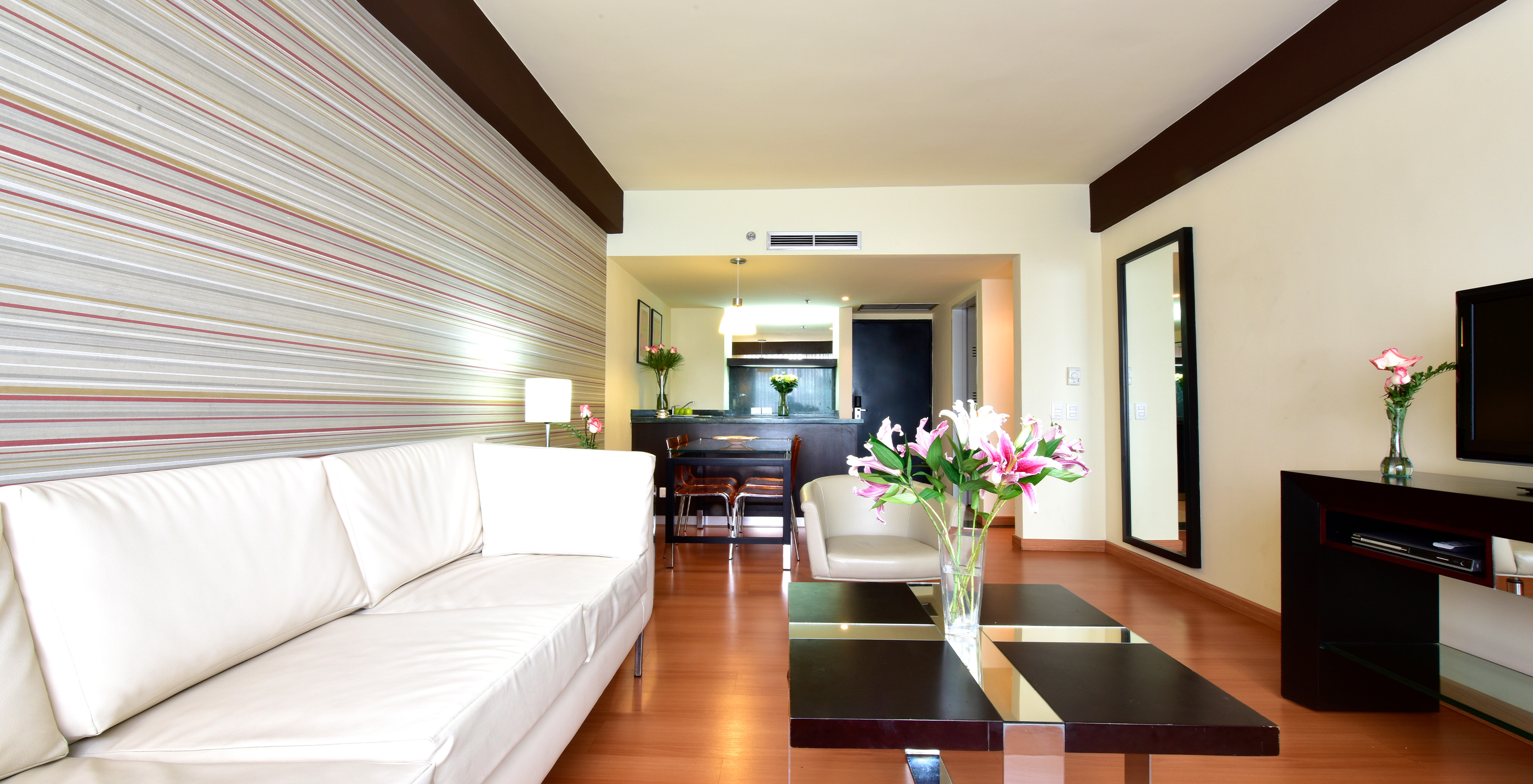 The Twin Junior Suite at Pestana Caracas has a living room with a two-seater white sofa, a TV, and a side table