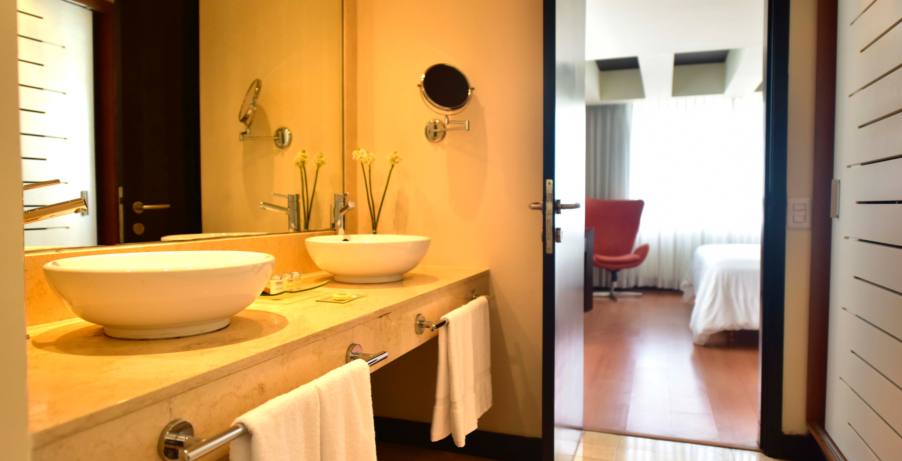 The Presidential Suite at Pestana Caracas has a bathroom with two sinks, a mirror, and a magnifying mirror