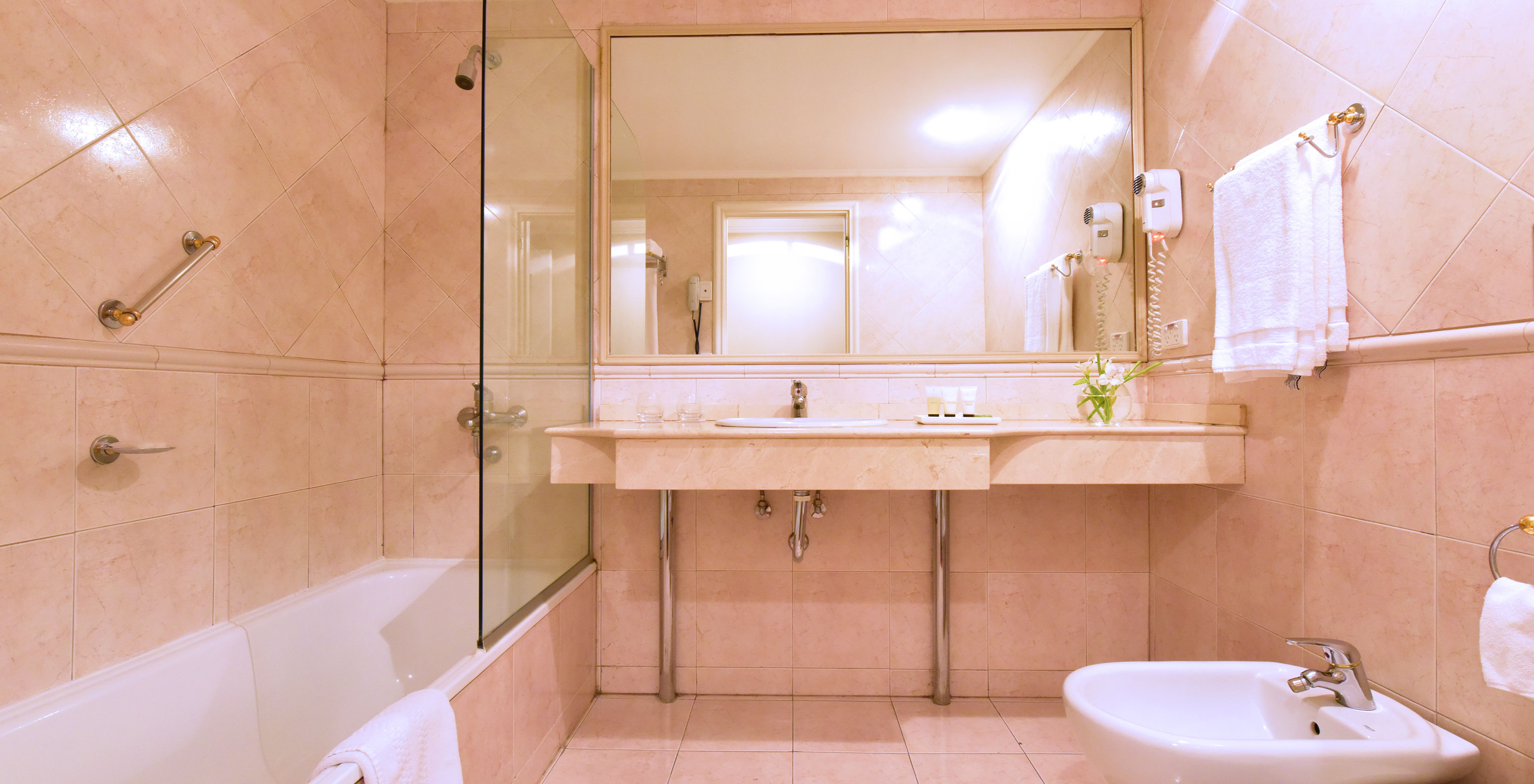 The Queen Deluxe Room at Pestana Buenos Aires has a bathroom with a sink, mirror, and a bathtub with a shower