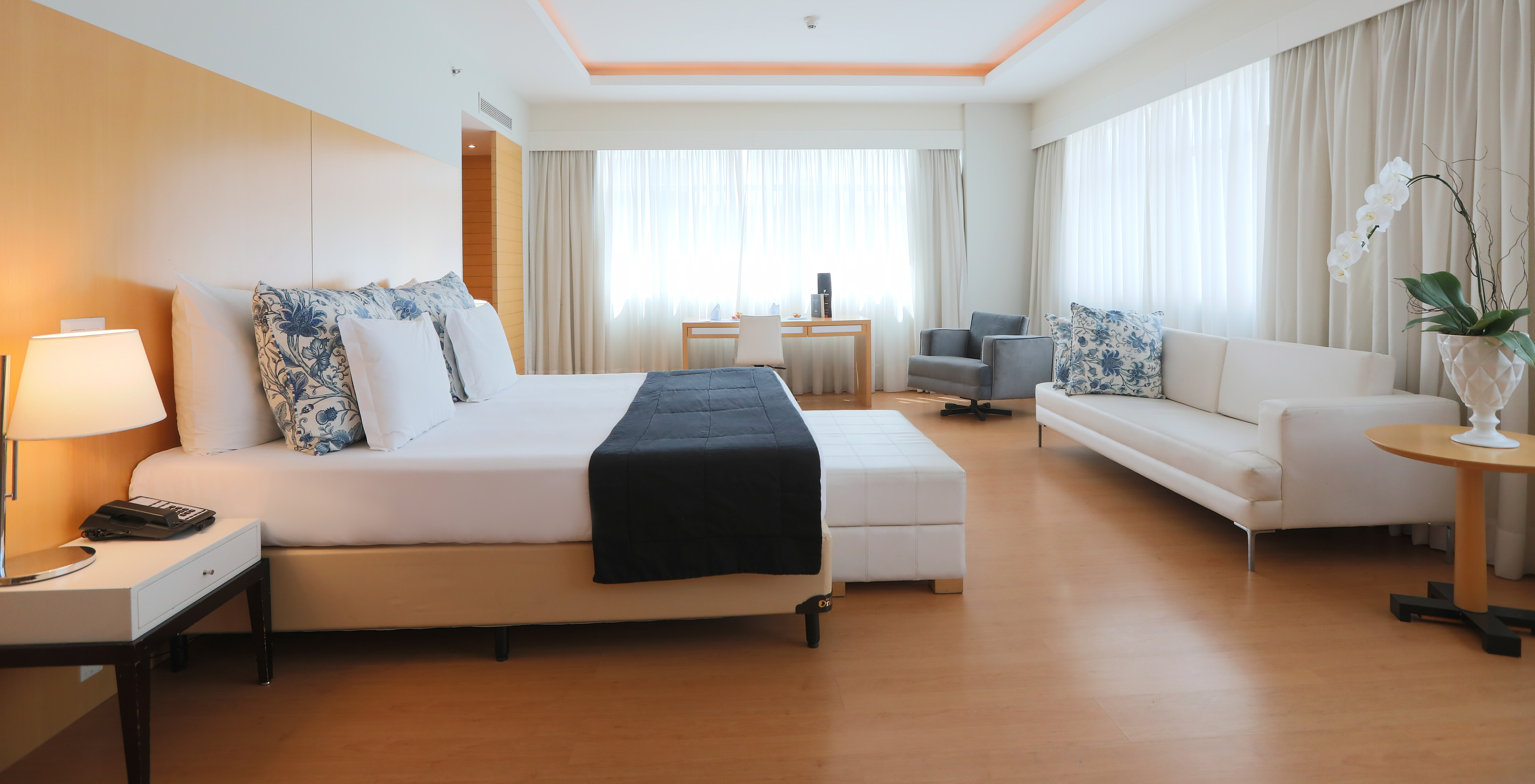 The Executive King Suite at Pestana Curitiba is spacious and bright, with a king-size bed, sofa, and a desk