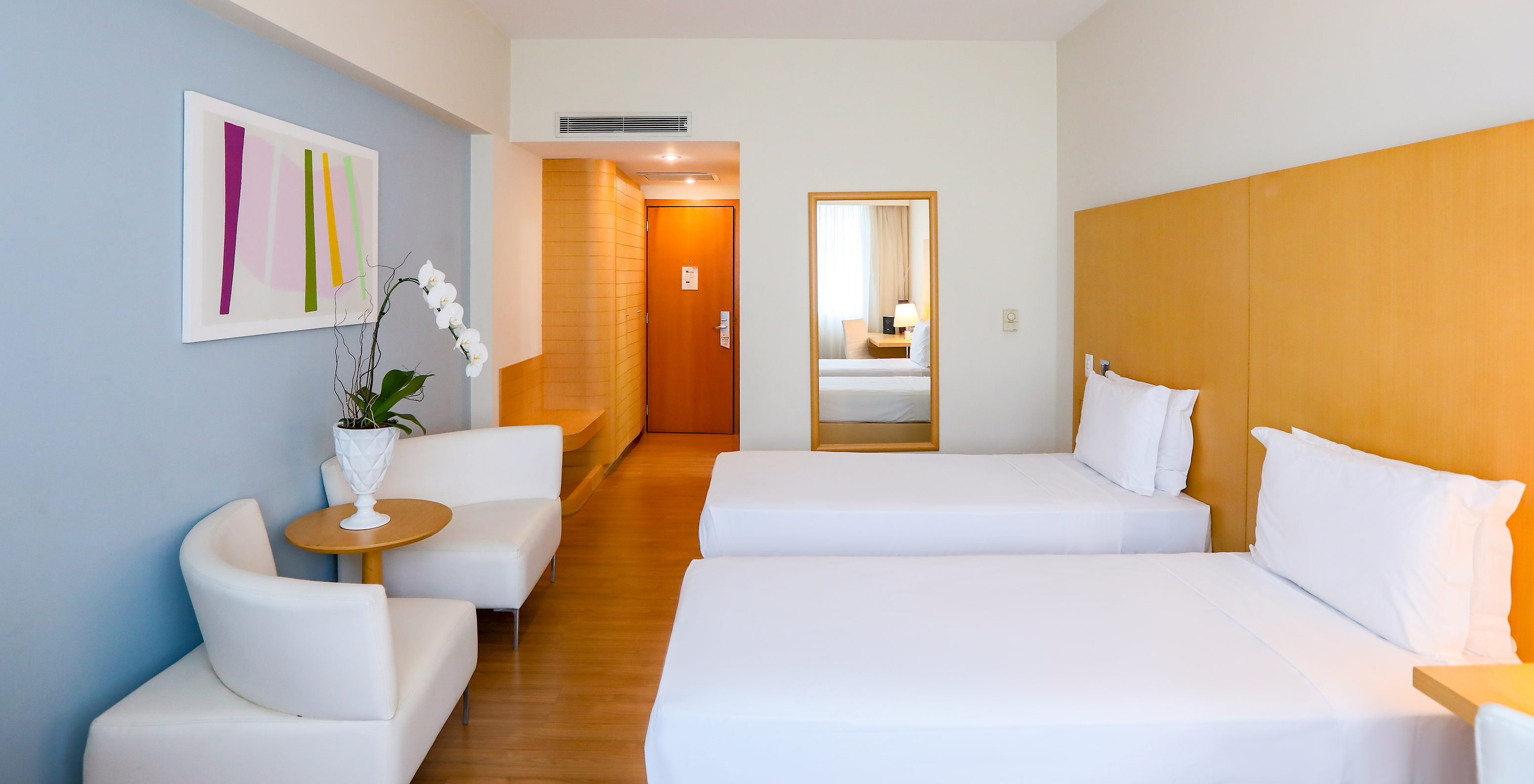 The Twin Superior at Pestana Curitiba has two single beds with sofas at the foot of the bed and a small table with flowers