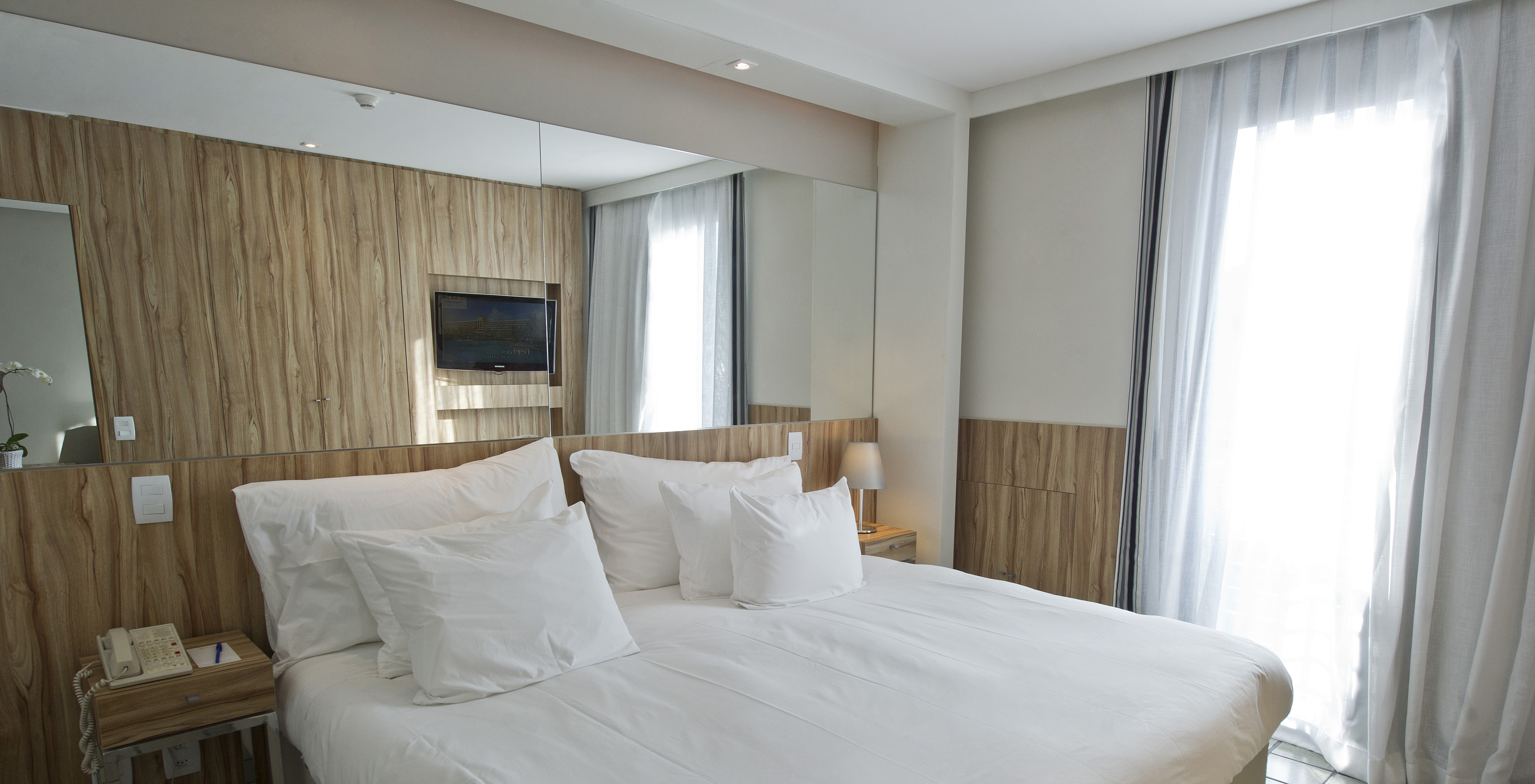 The Suite of Pestana Rio Atlântica has a double bed with a mirror on the headboard and two nightstands