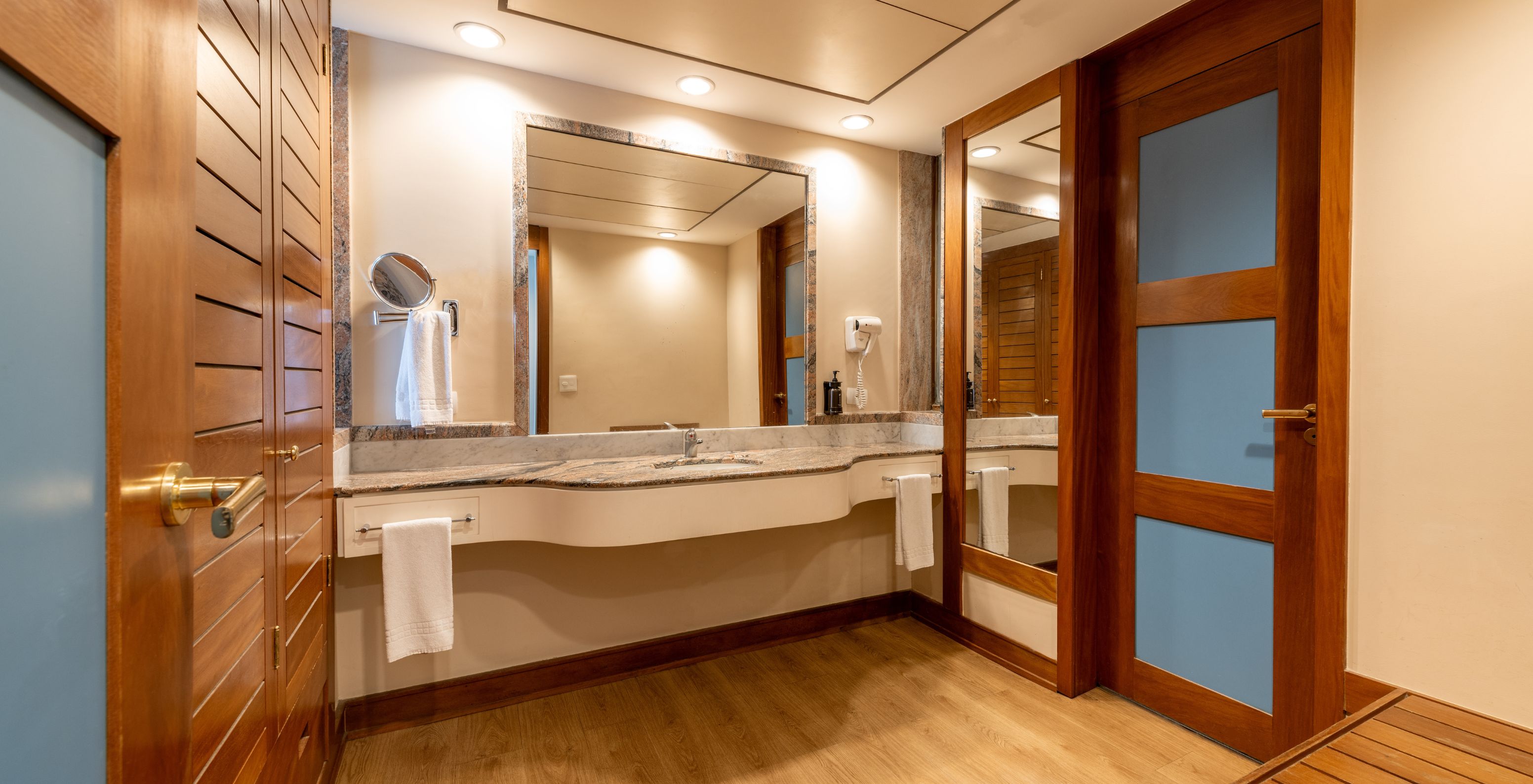 The Family Room at Pestana São Paulo has a bathroom with a large sink with a mirror, a hairdryer, and towels