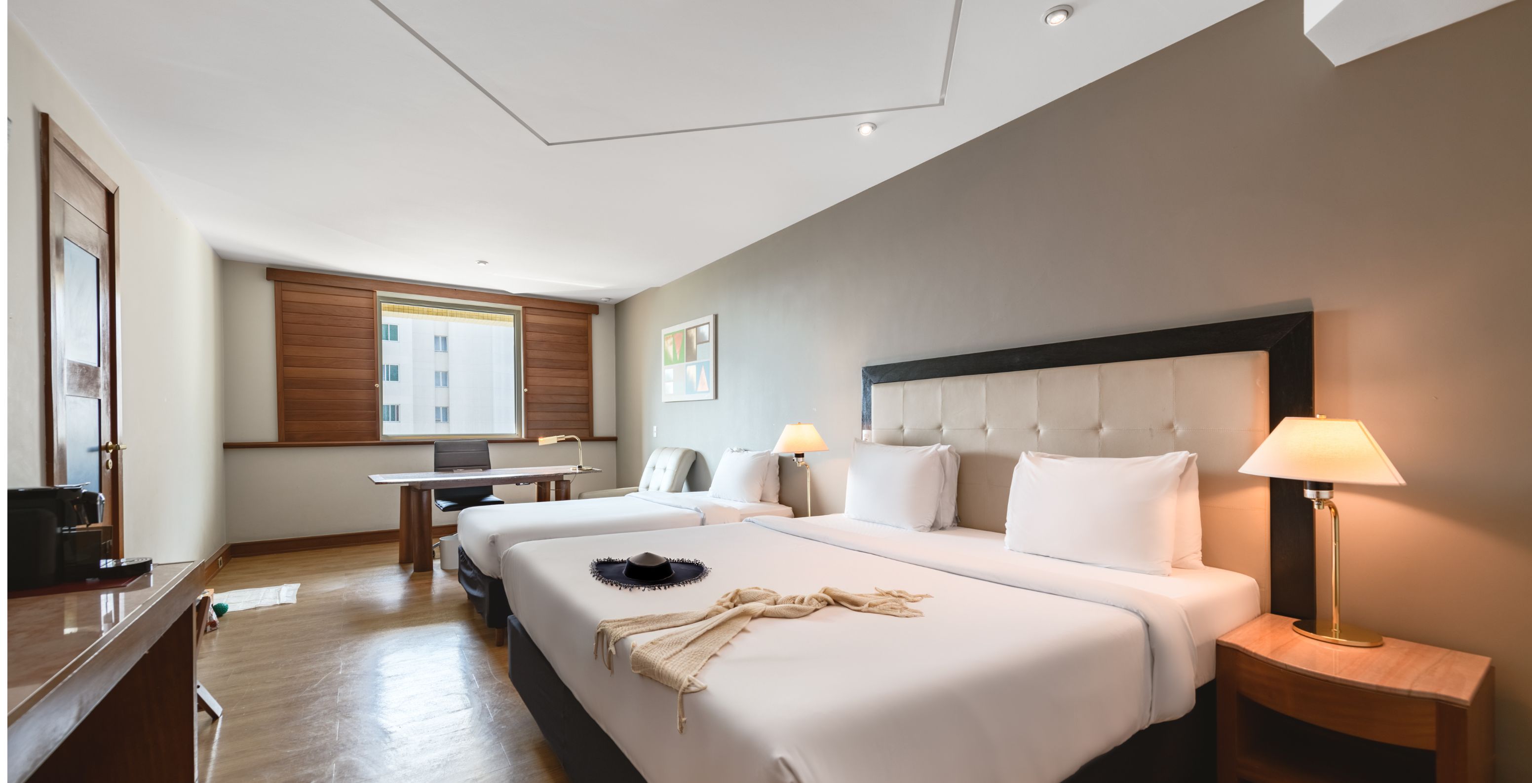 The Family Room at Pestana São Paulo has a double bed, two bedside tables, a desk, and a window