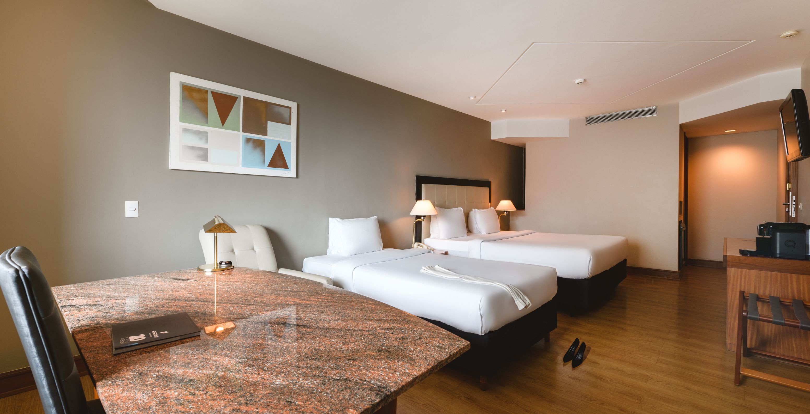 The Family Room at Pestana São Paulo has a stone desk, a double bed, and a single bed