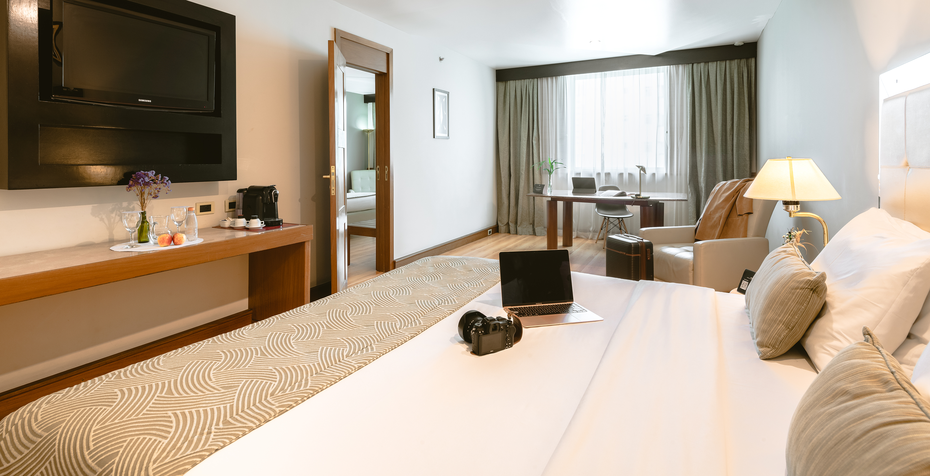 The Executive Suite of Pestana São Paulo has a room with a double bed, two bedside tables, a desk, and a window