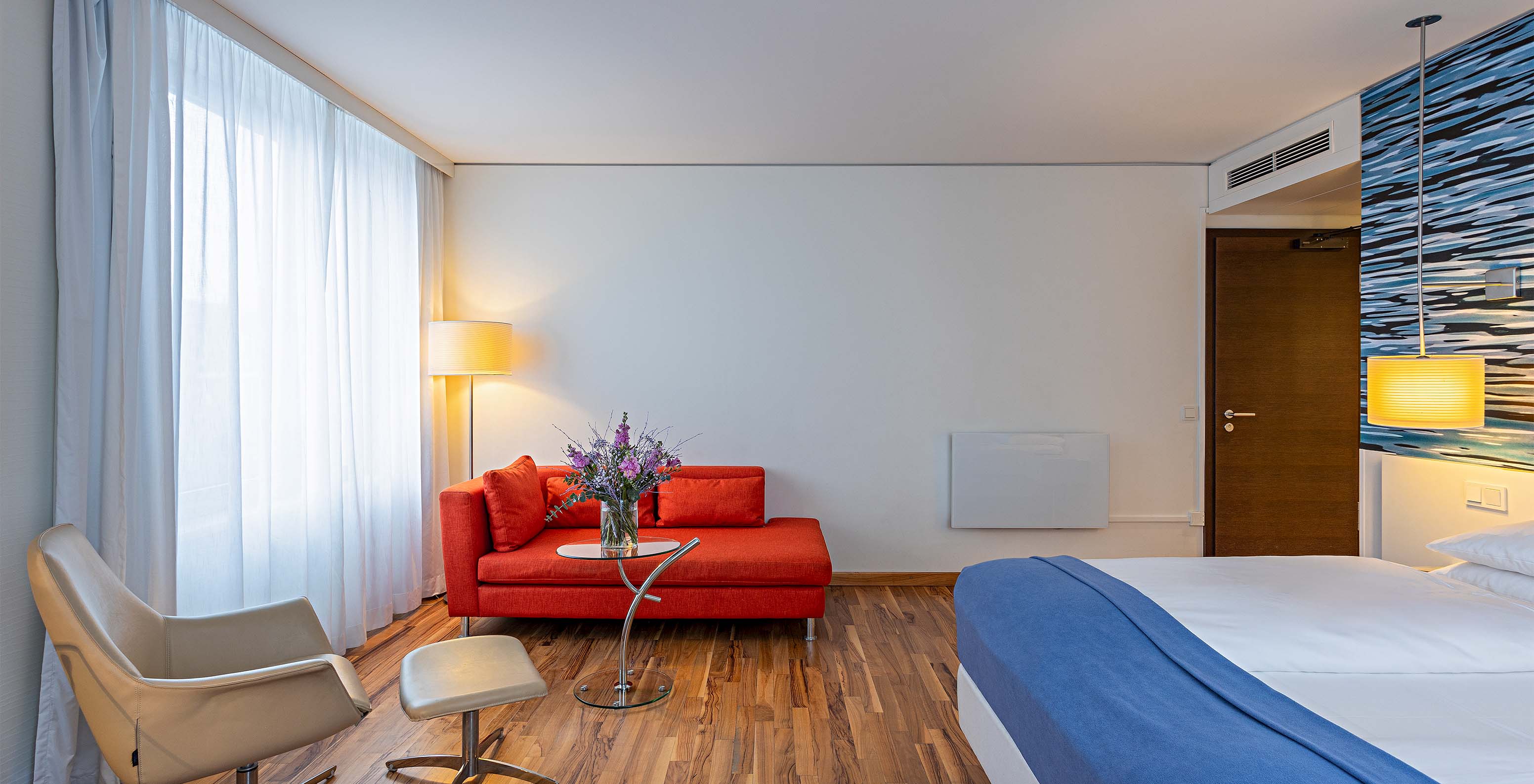 Grand Deluxe room at Pestana Berlin Tiergarten has a double bed, a sofa, coffee table, and an armchair