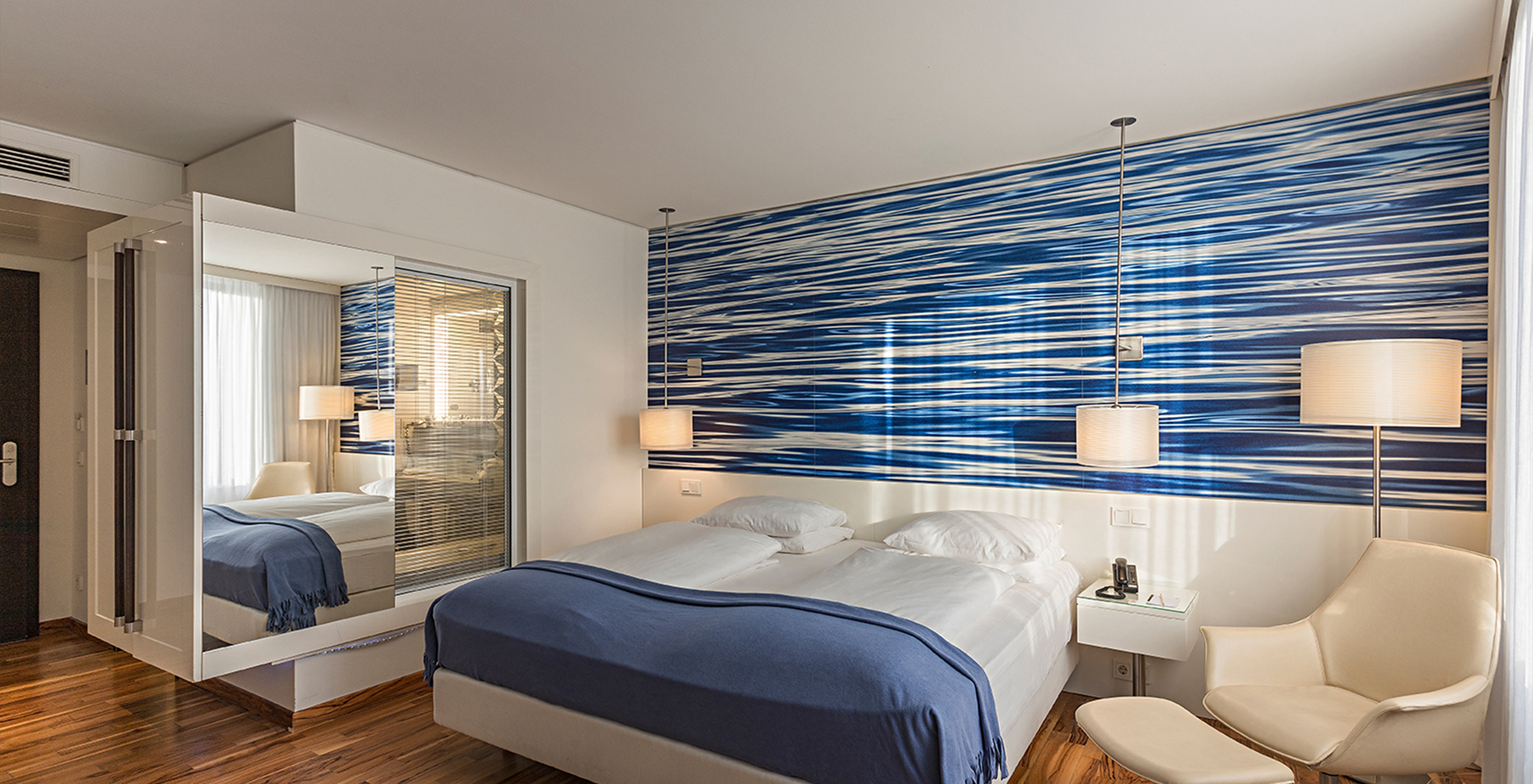 Deluxe room at Pestana Berlin Tiergarten has a double bed, bedside table with phone, and a sofa