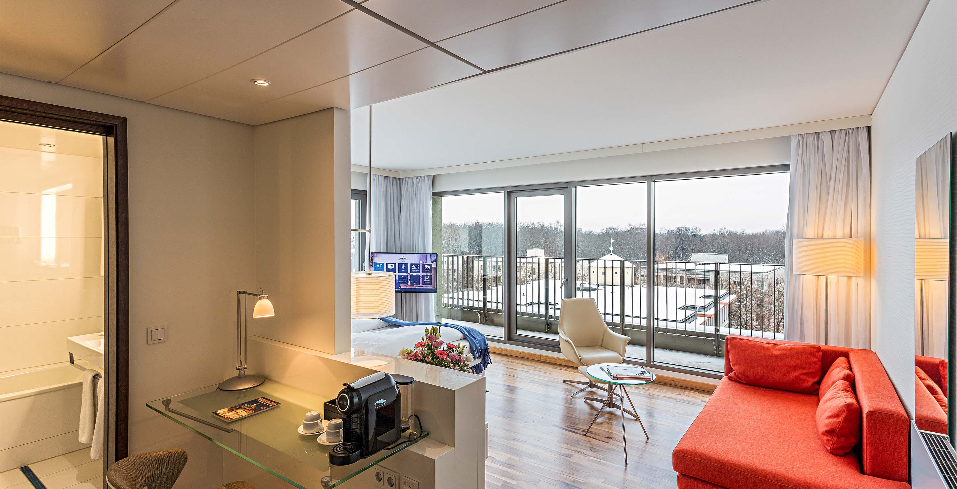 Family Deluxe room at Pestana Berlin Tiergarten has a desk, coffee machine, sofa and an armchair