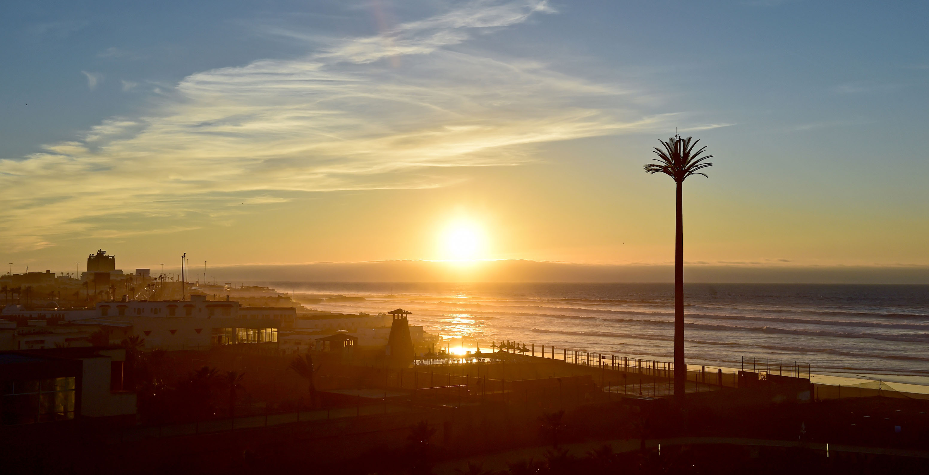 City view with sunset in the background, sunlight reflecting on ocean waves