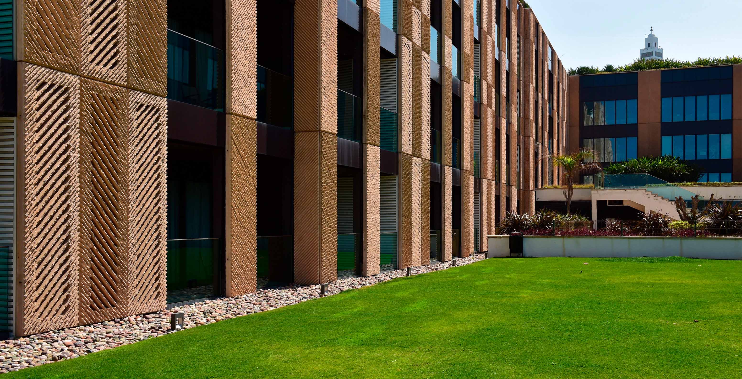 View of the hotel’s side exterior, showing facades and grassy gardens