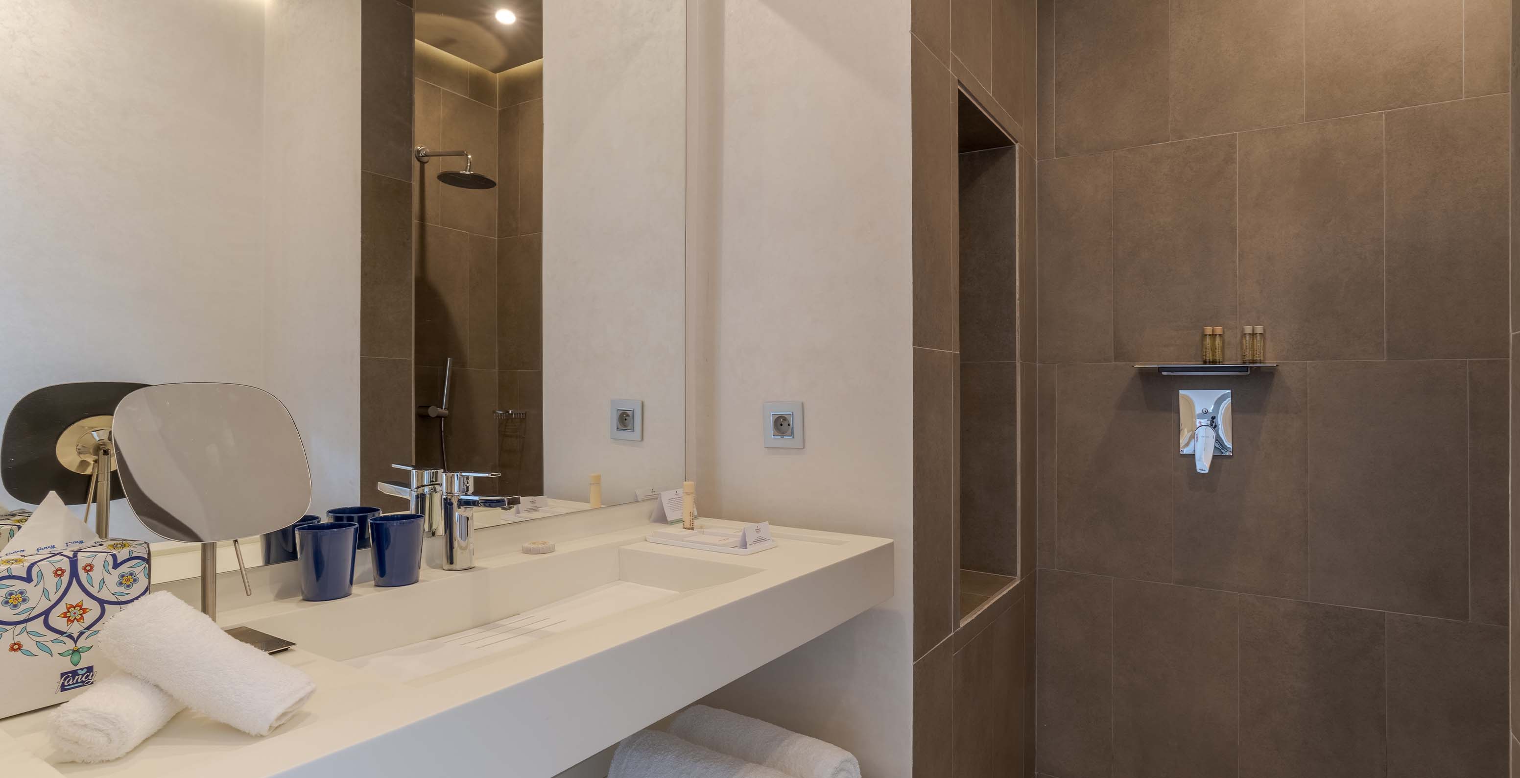 The CR7 Suite Avenue at Pestana CR7 Marrakech has a bathroom with a walk-in shower and a sink with a large mirror