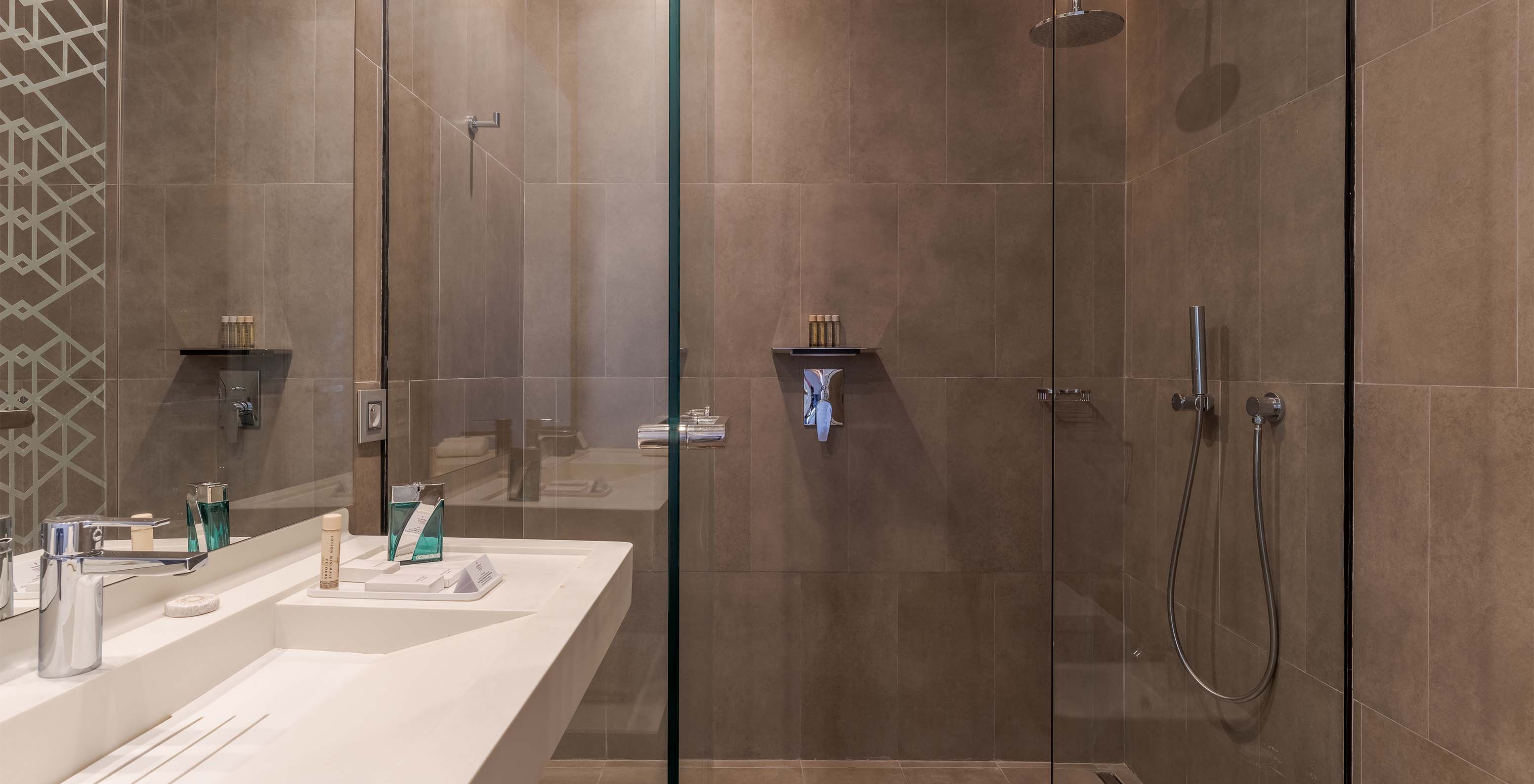 The CR7 Superior at Pestana CR7 Marrakech has a bathroom with a walk-in shower and a sink with a large mirror