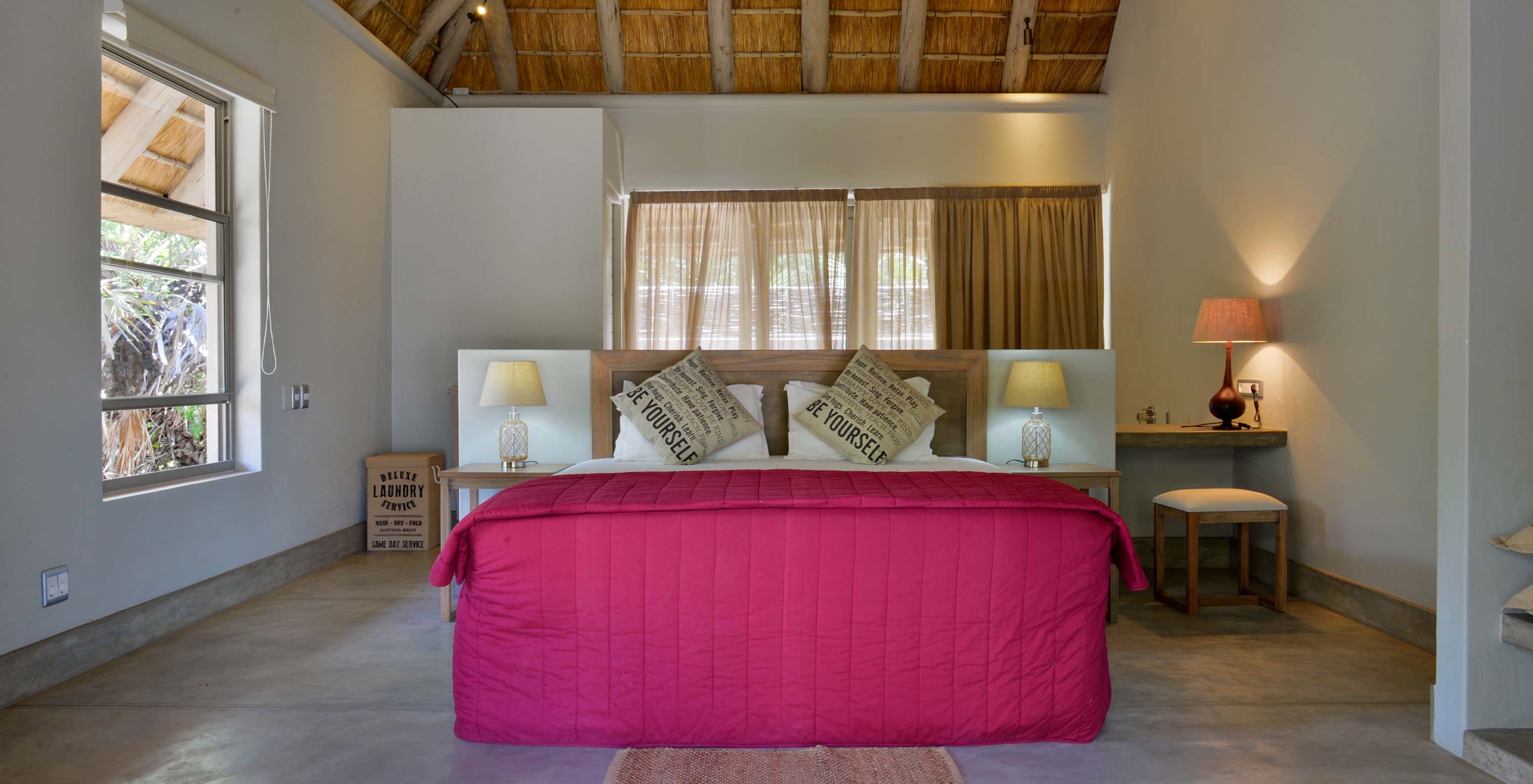 T2 Villas at Pestana Bazaruto Lodge are quite spacious with a double bed with red bedspread and windows around