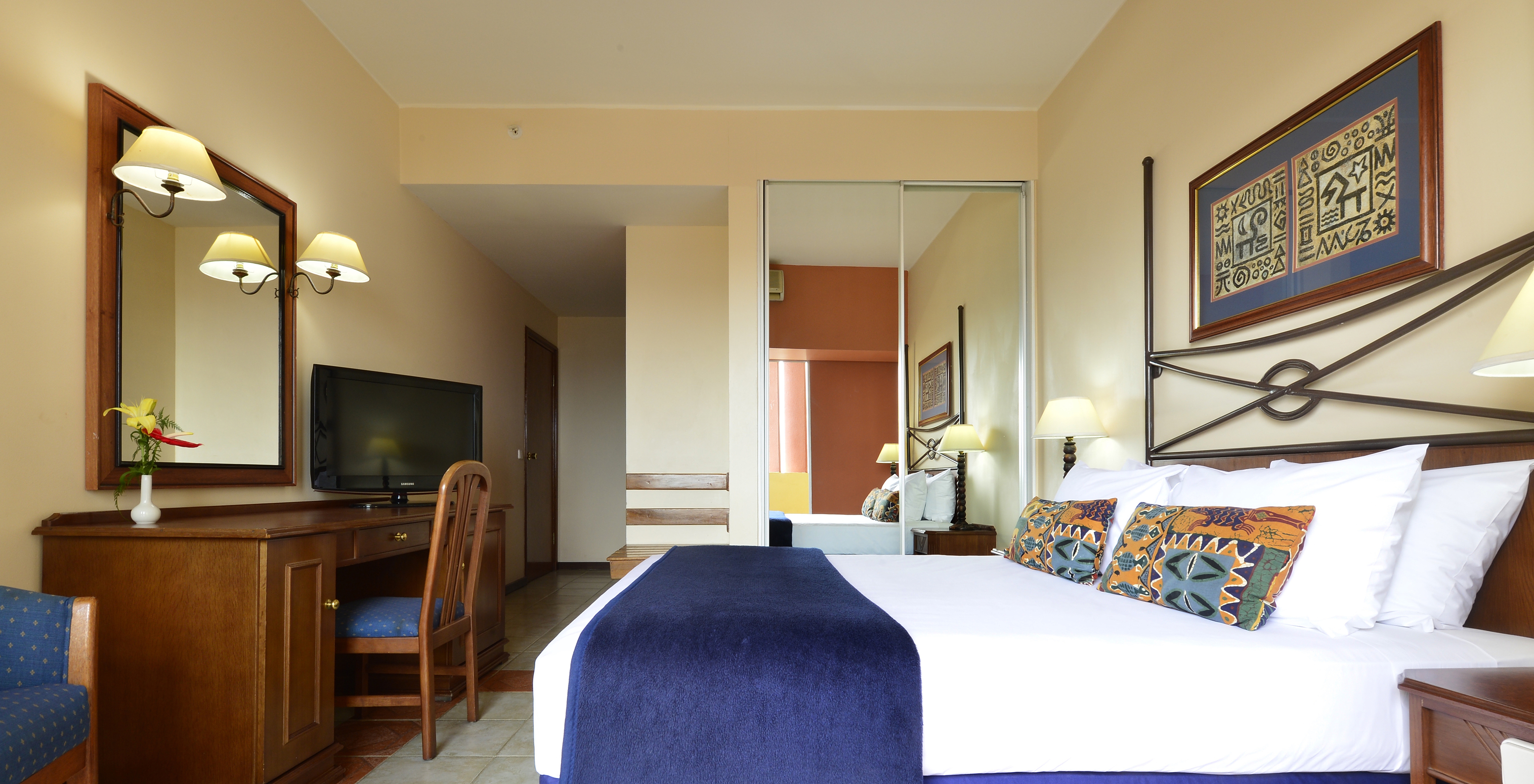 The Standard Double of Pestana Rovuma has a double bed, a wardrobe with mirror, a desk, and a television