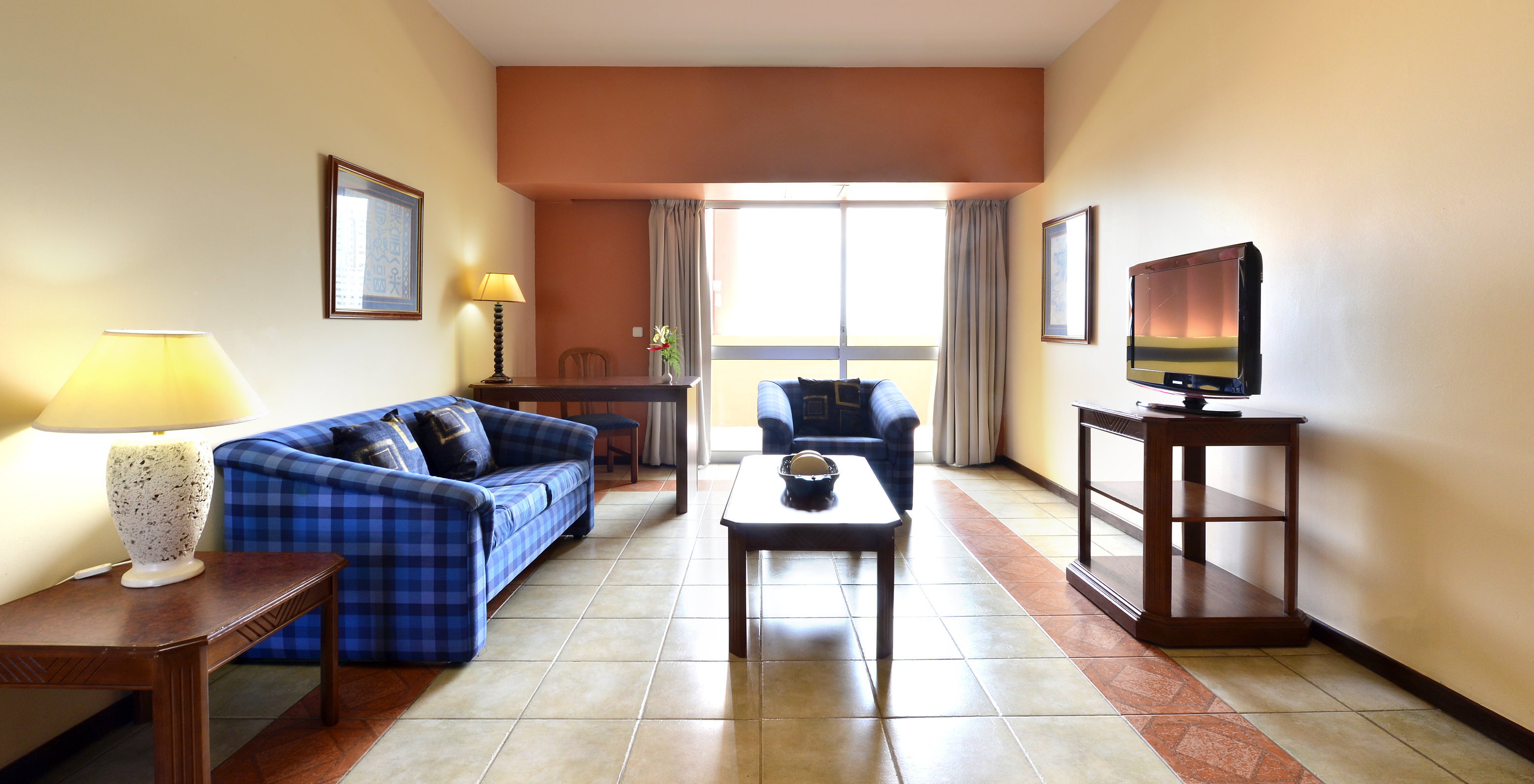 The Executive Suite of Pestana Rovuma has a living room with sofa, television, and a large window with balcony