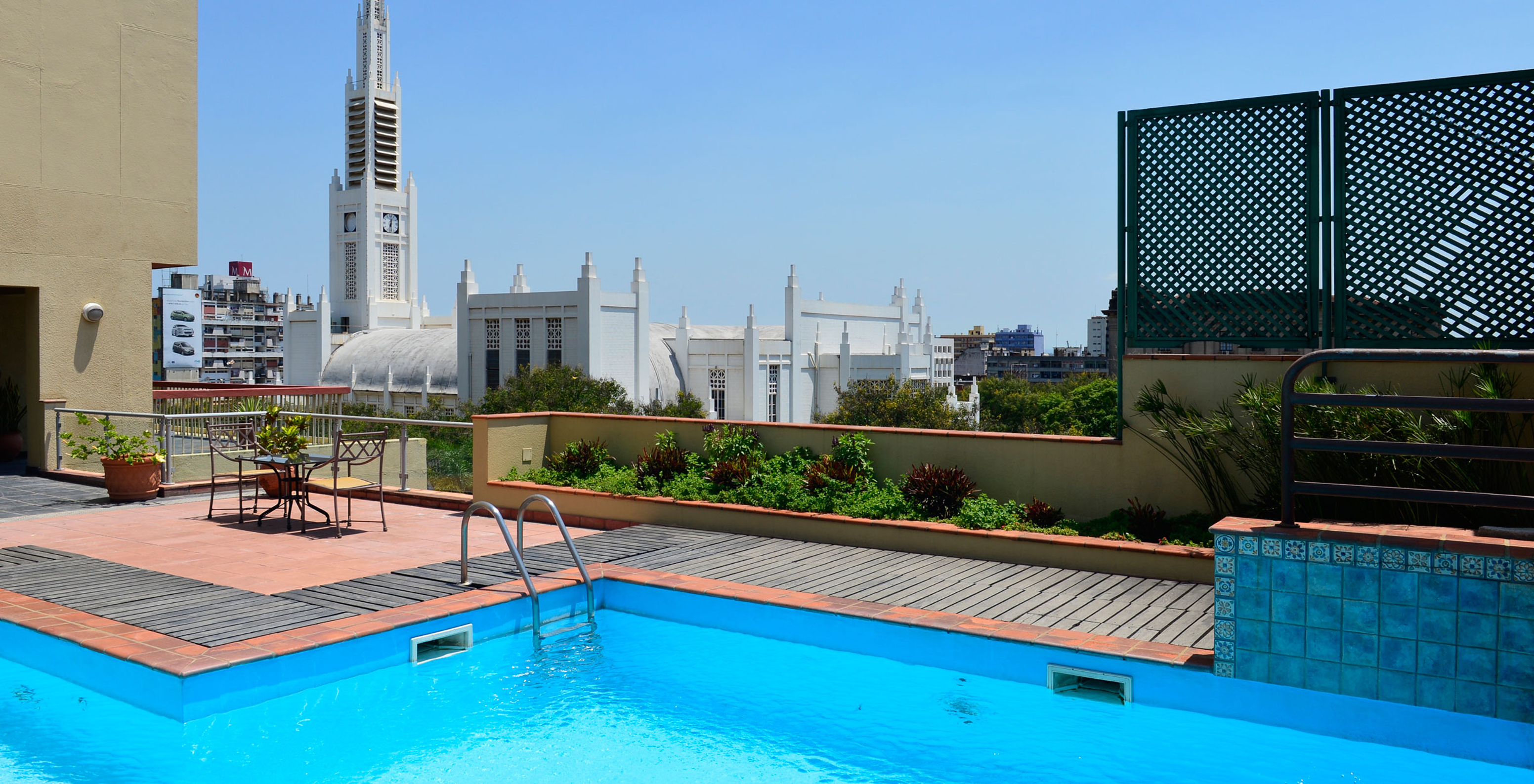 Rooftop with outdoor pool, tables, and views of the Cathedral of Maputo in a hotel in central Maputo