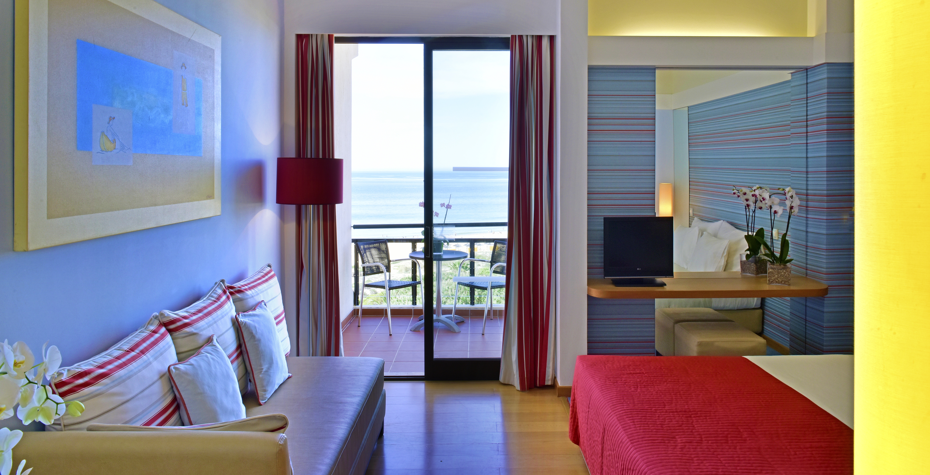 The Deluxe Sea View room at Pestana Dom João II includes a sofa and a balcony with tables and chairs overlooking the sea