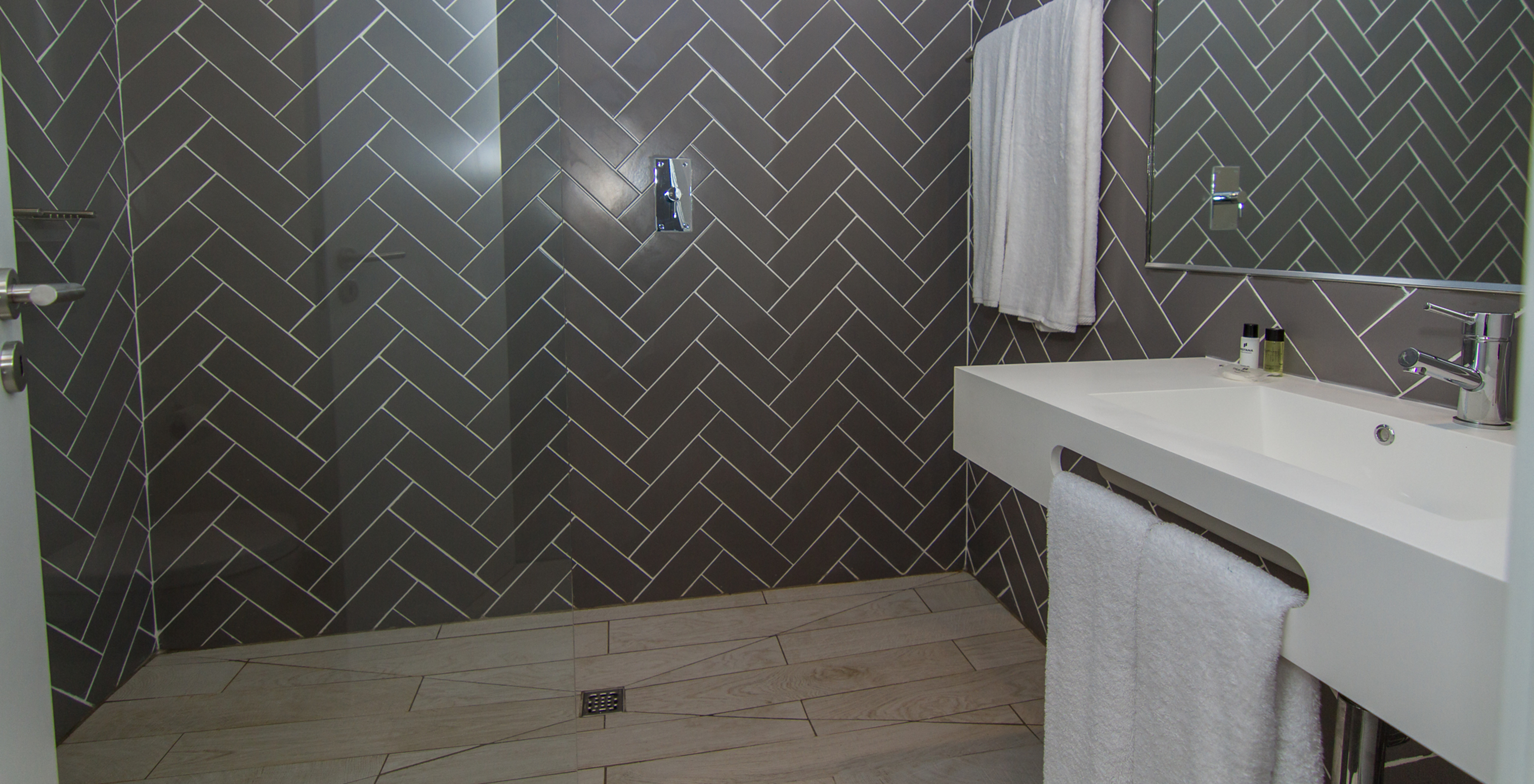 The Studio at Pestana Gramacho Residences has a bathroom with a walk-in shower, sink, mirror, and towels