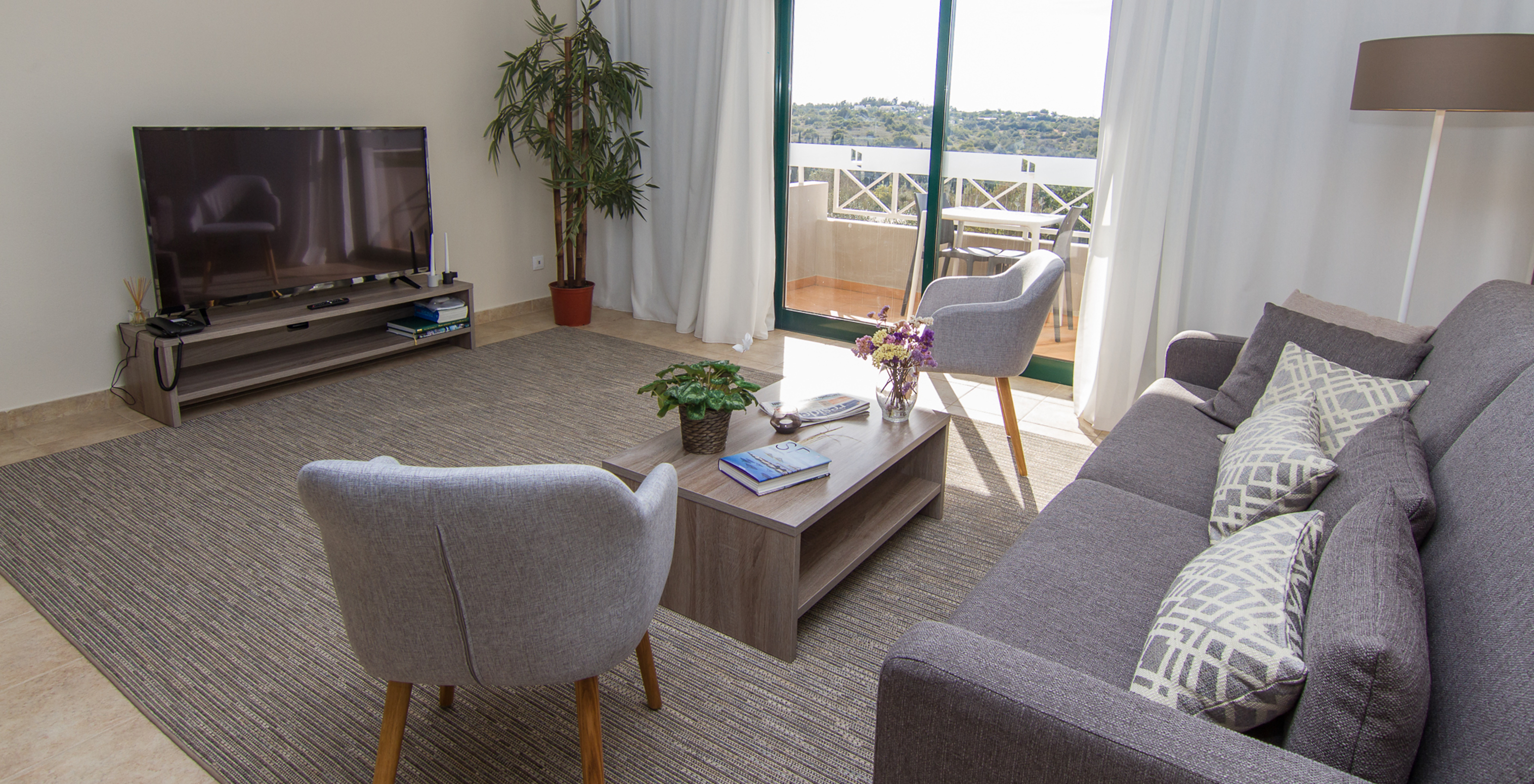 The T2 Apartment at Pestana Gramacho Residences includes a living room with a sofa, television, and a window with a balcony